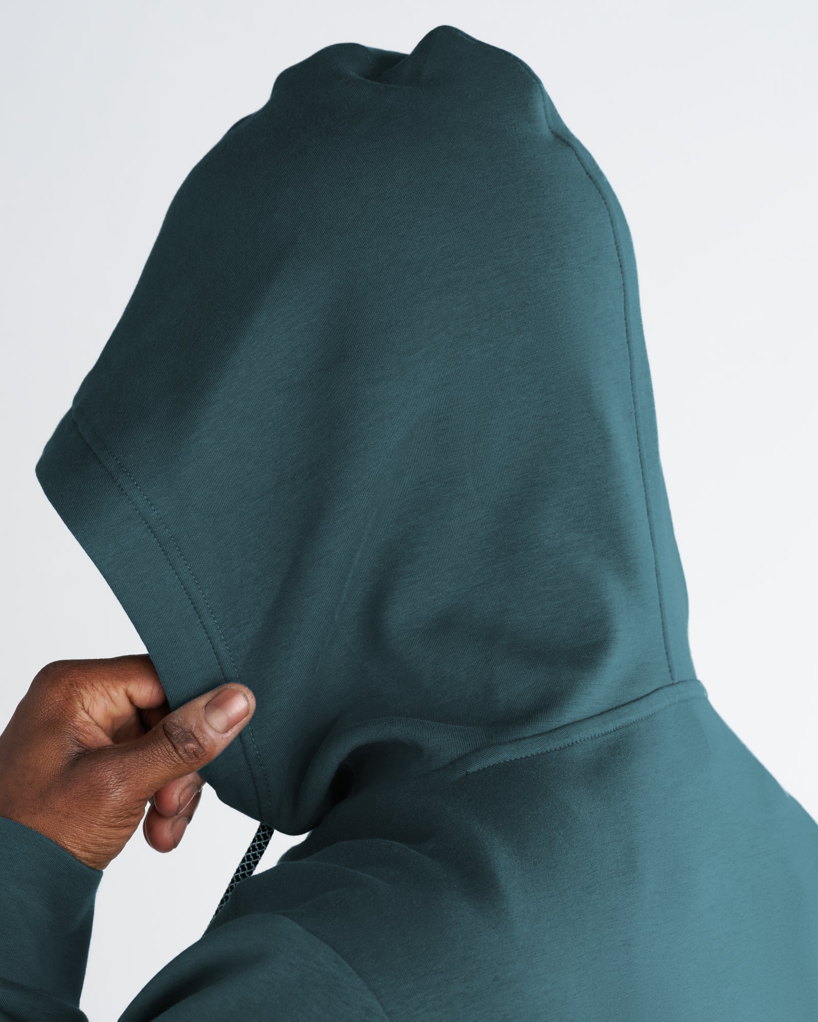 Close-up detail of the Pro-Tech Hoodie in Teal showing the oversized hood structure and drawcord.