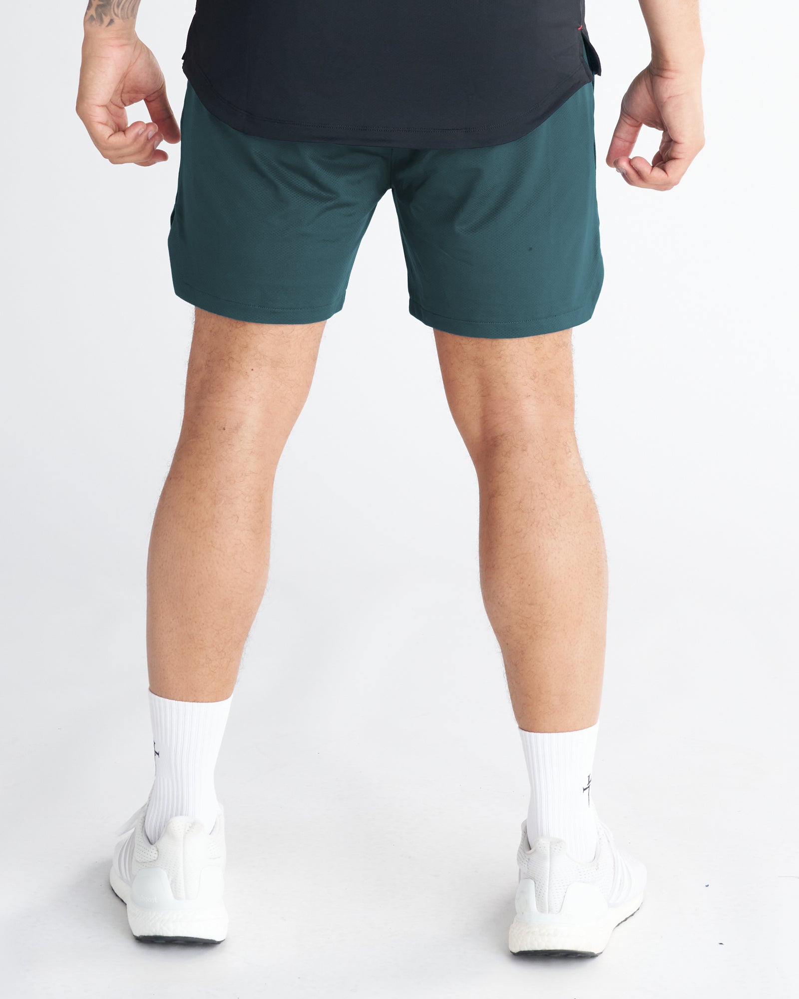 Back view of model wearing Pro-Tech 2.0 Liner Short in Teal, paired with white sneakers and socks.