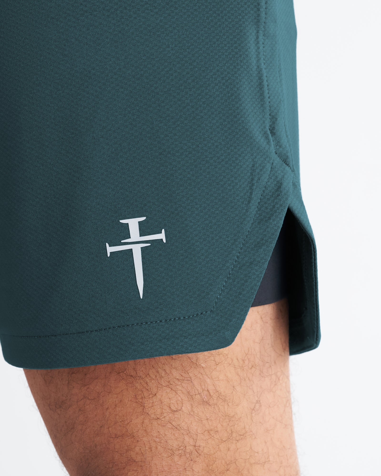 Close-up detail of the Pro-Tech 2.0 Liner Short in Teal showing the Three Nails logo on the hem.