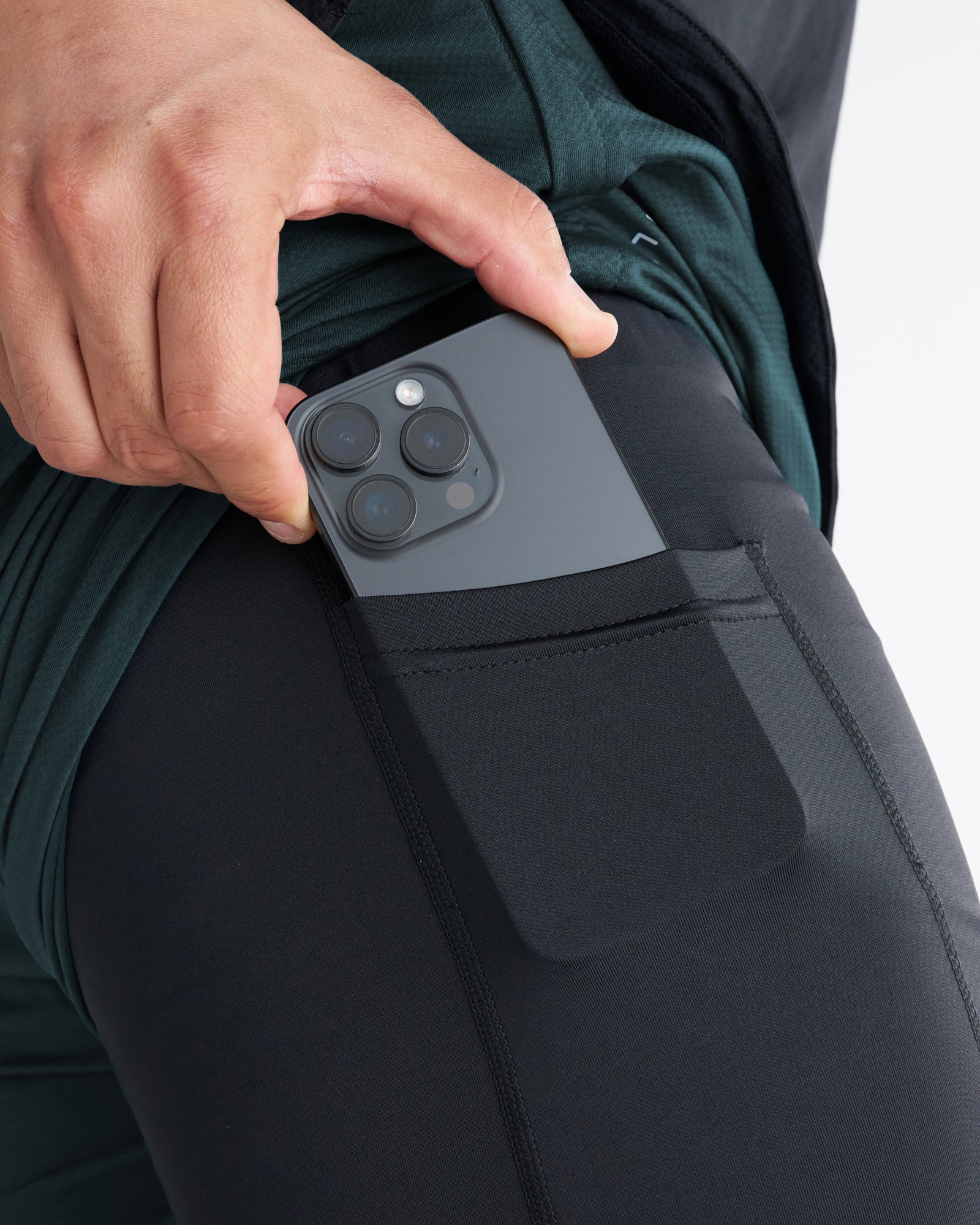 Close-up detail shot of the Pro-Tech 2.0 Liner Short in Teal showing a phone being inserted into the side thigh pocket.