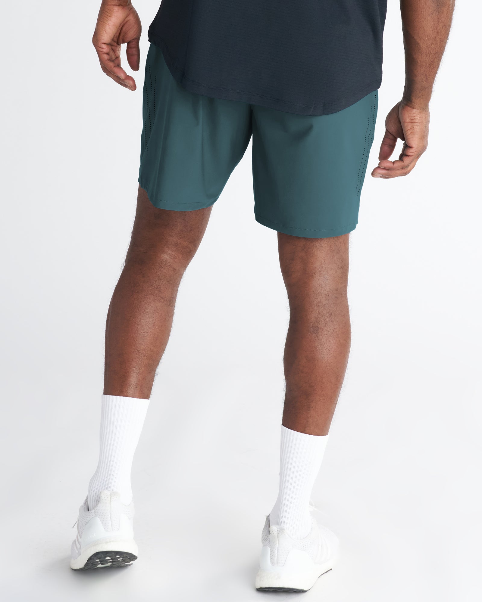 Back view of the Vapor-Lite Hybrid Short in Teal, showing perforated side panels, worn with white sneakers.