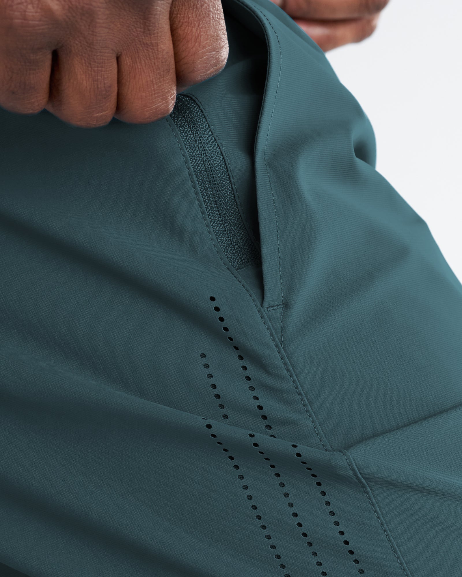 Close-up detail of the Vapor-Lite Hybrid Short in Teal showing ventilation perforations and interior pocket opening.