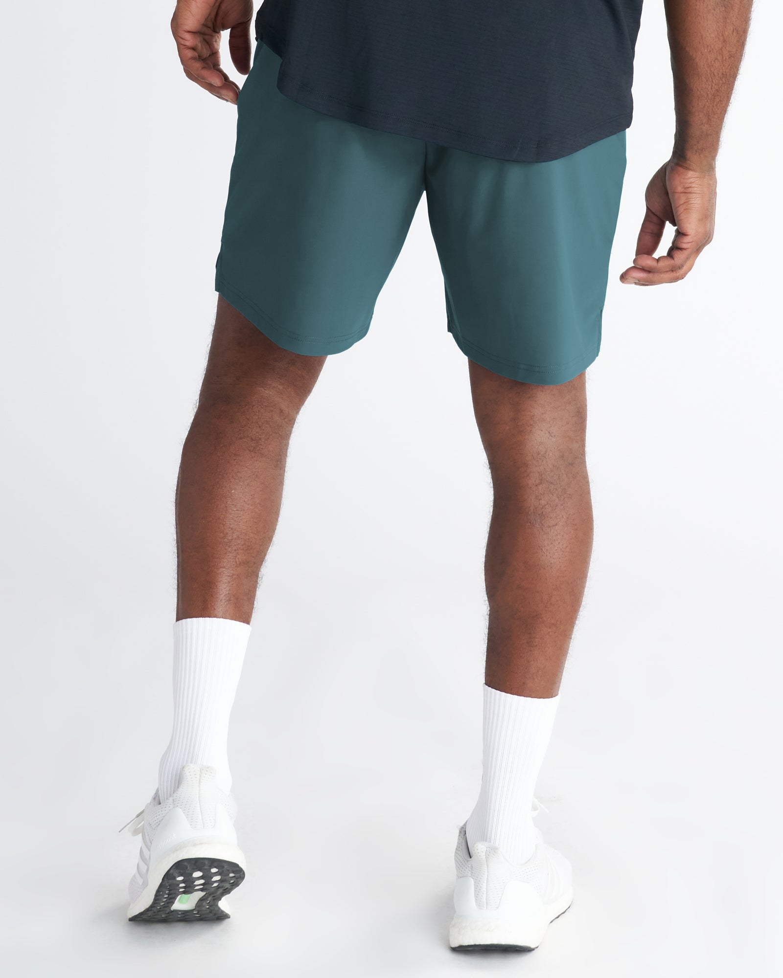 Back view of model wearing Vapor-Lite Liner Short Cross in teal with white sneakers and socks.
