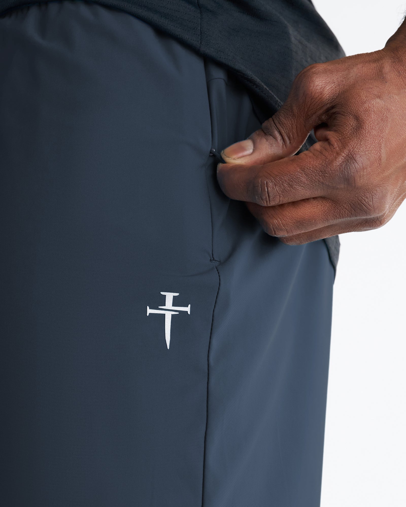 Close-up detail of Vapor-Lite Liner Short in Midnight Navy showing side pocket opening and embroidered cross logo.