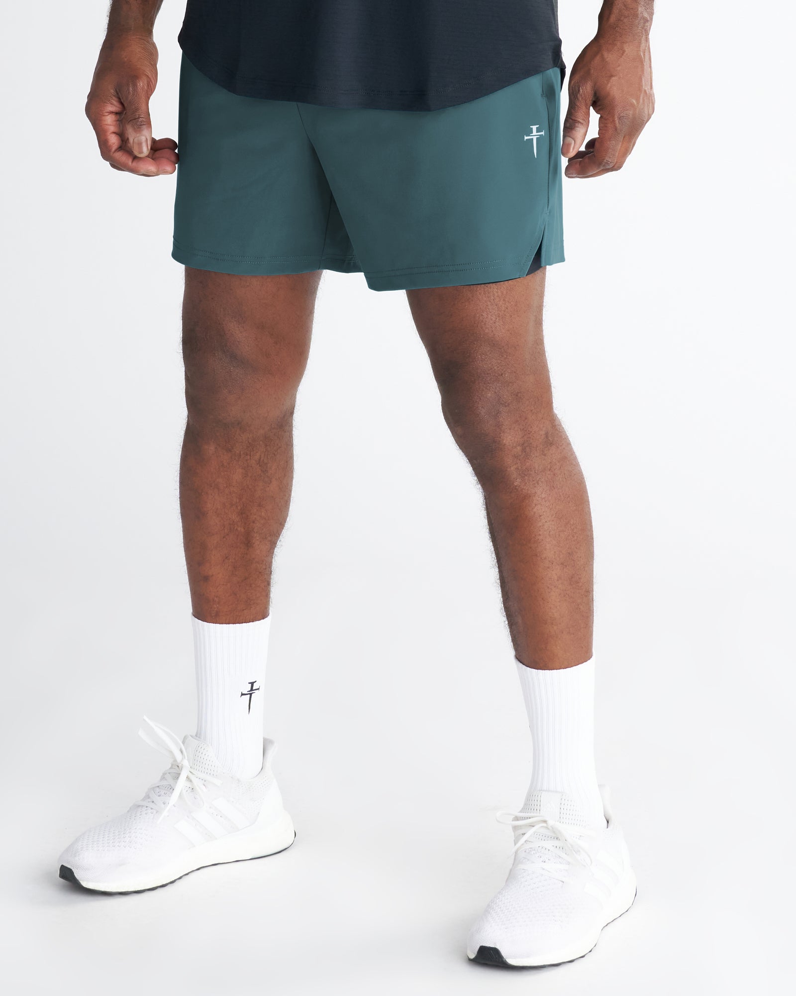 Man wearing Vapor-Lite Liner 5" Short in teal, front view, paired with white sneakers and socks.