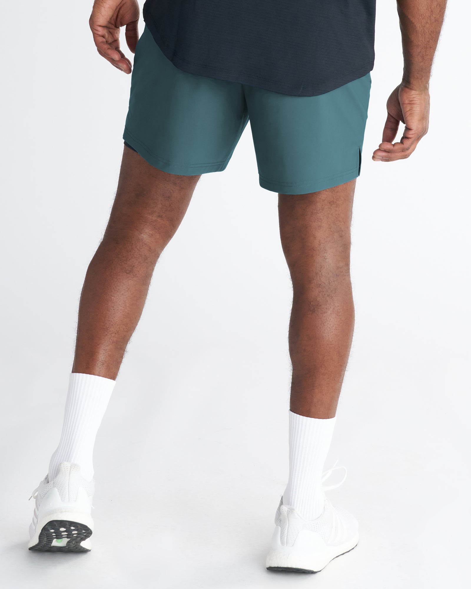 Back view of model wearing Vapor-Lite Liner 5" Short Cross in teal with white sneakers and socks.