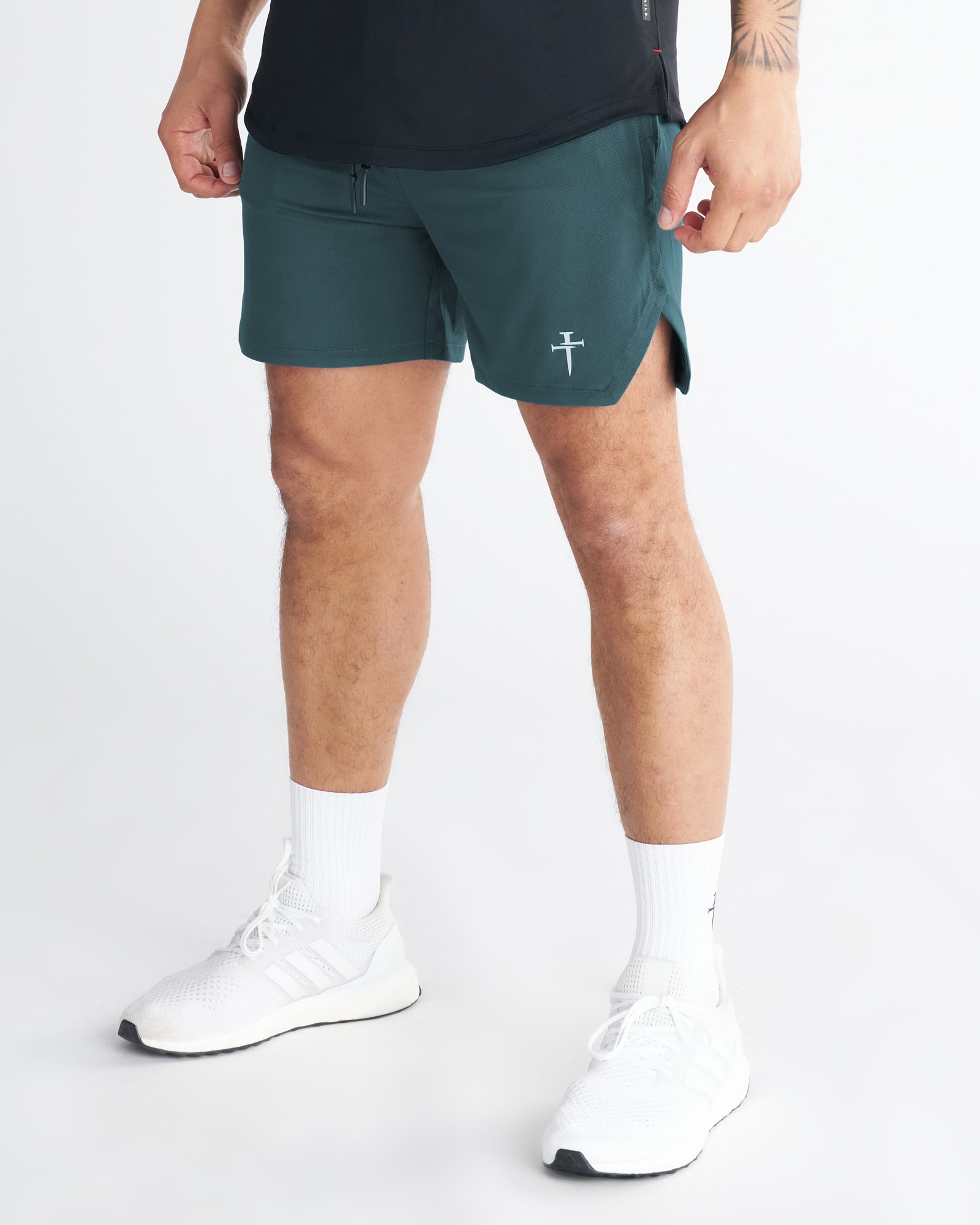 Pro-Tech 2.0 Linerless Short in Teal on a model at a slight side angle, showing the short hem, split hem detail, and logo.