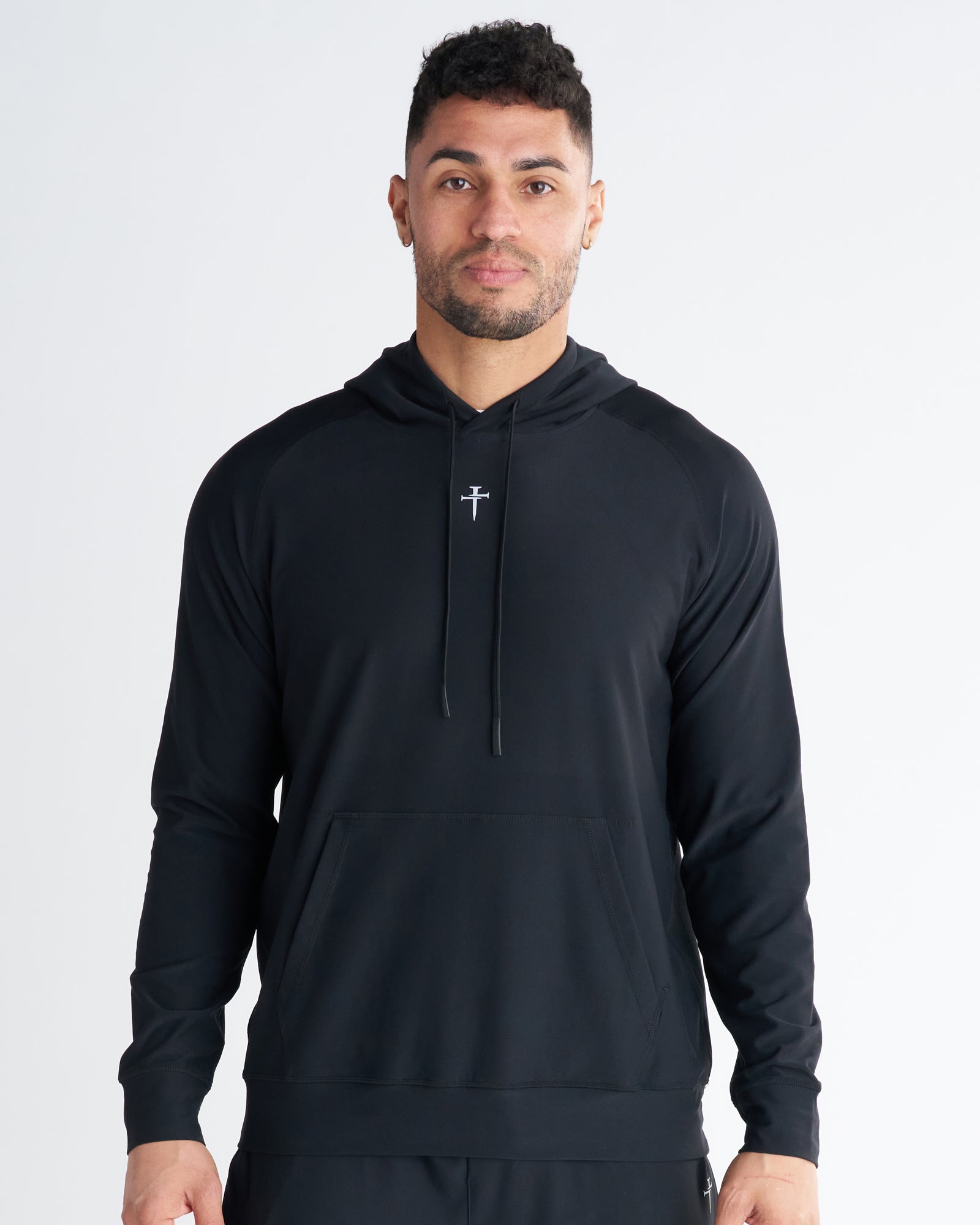 Haven Performance Hoodie in black, front view on male model, featuring center cross logo and kangaroo pocket.