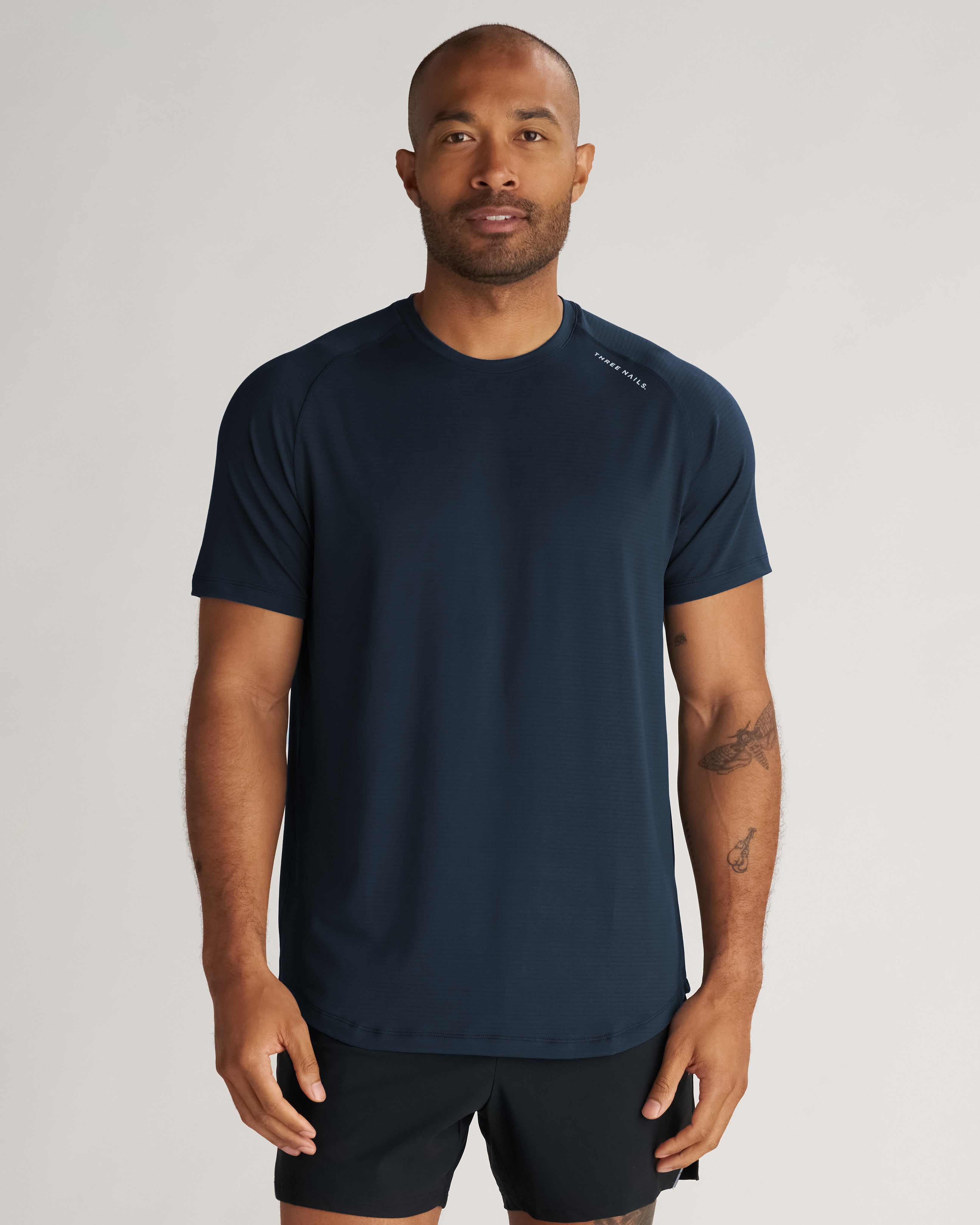 Aion-Lite Tee in Midnight Navy worn by a male model, front view, paired with black shorts.
