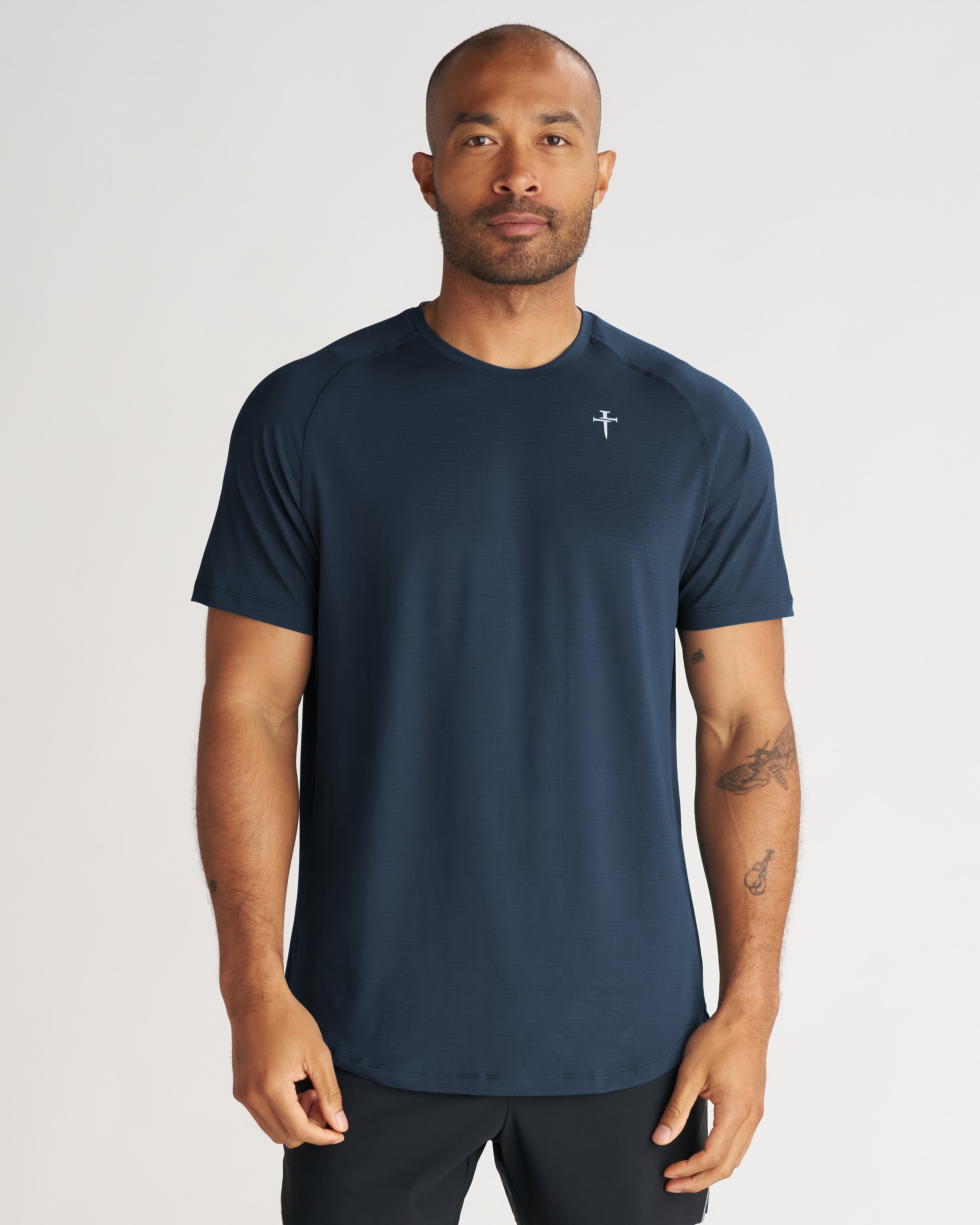 Man wearing Aion-Lite Tee Cross in Midnight Navy, front view, crew neck, short sleeve, small cross logo on chest.