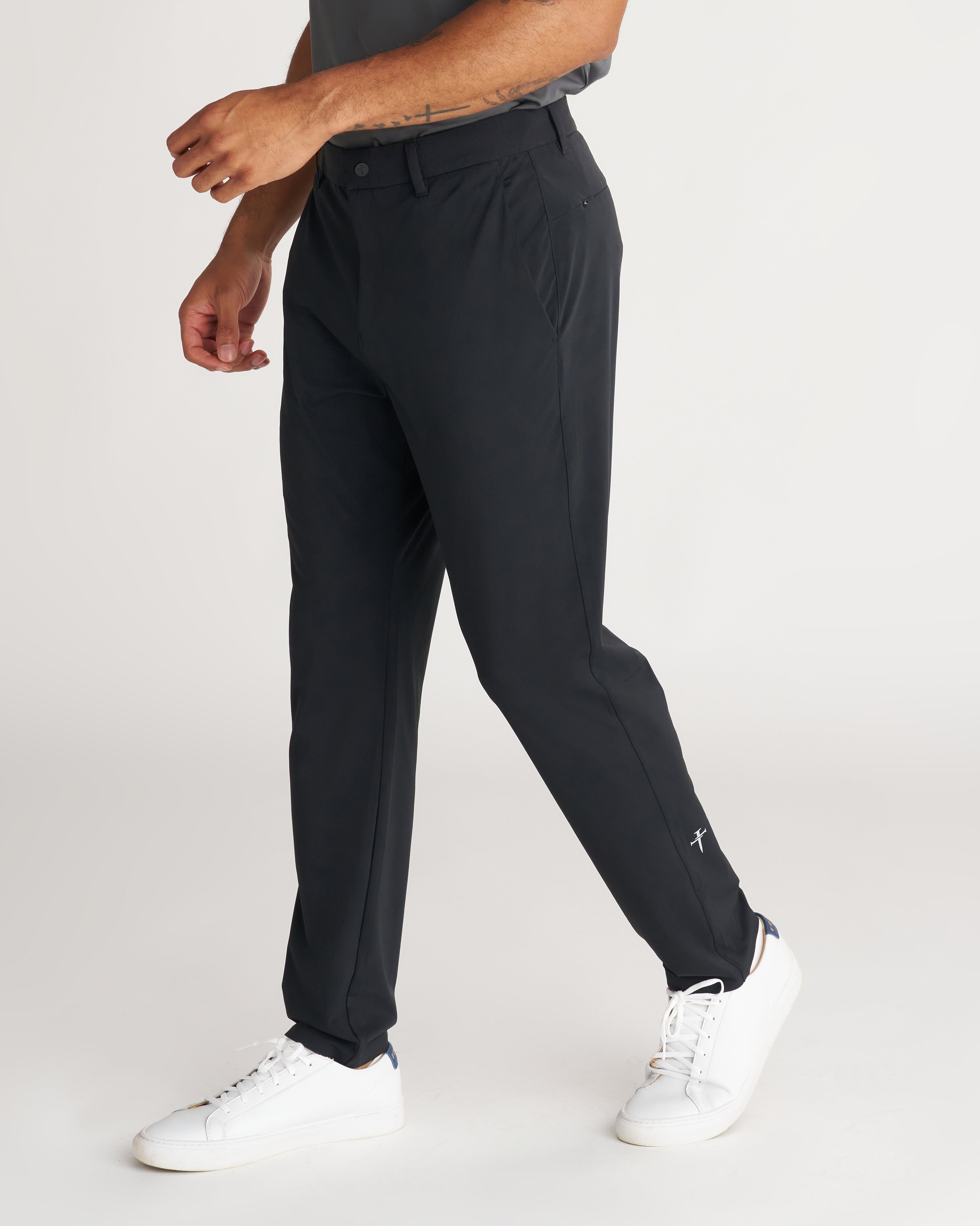 Links Golf Pant in black on a male model at a side angle, showing slim tapered fit and small logo near hem.