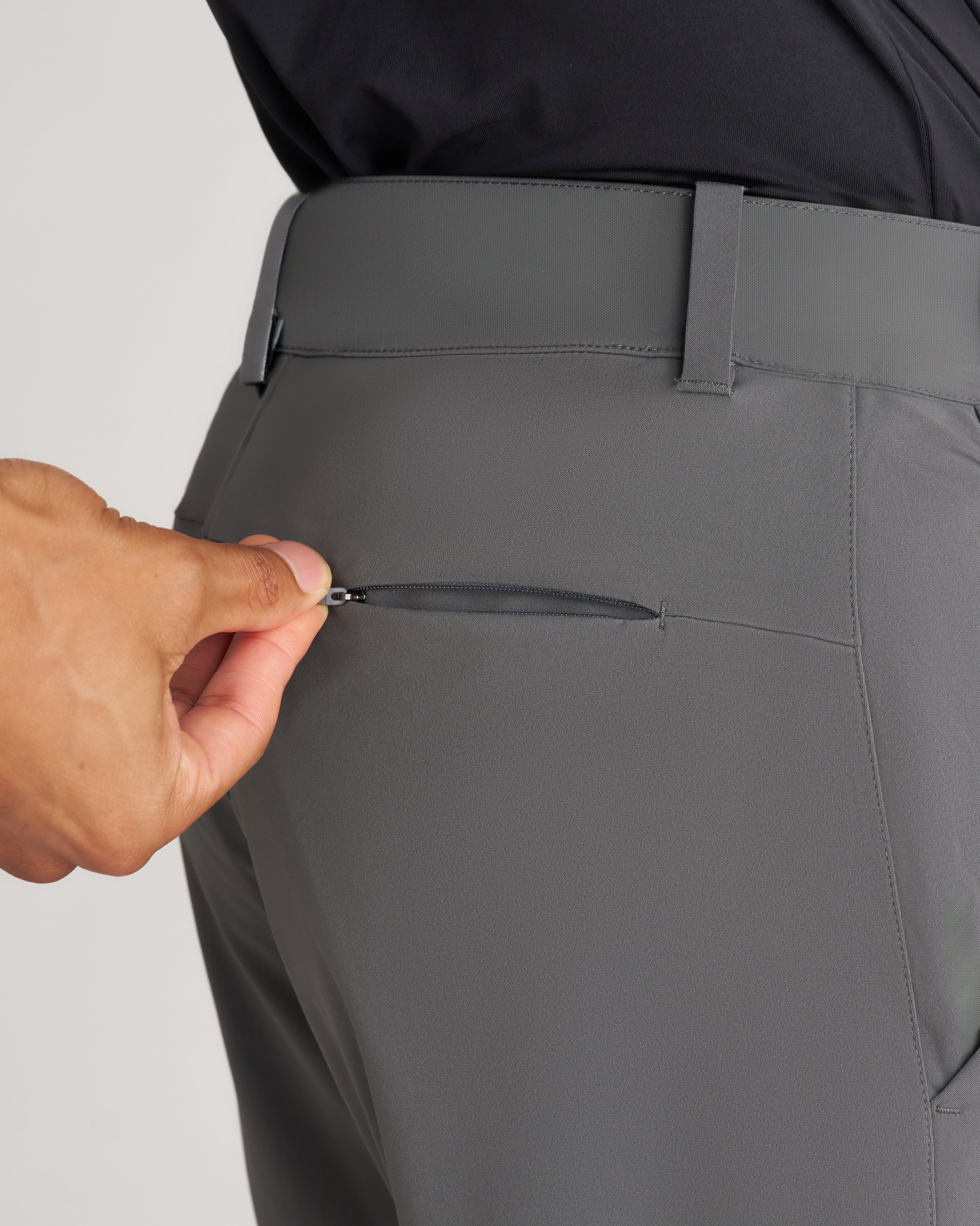 Close-up of Links Golf Pant in Space Grey showing a zippered back pocket being opened by hand.
