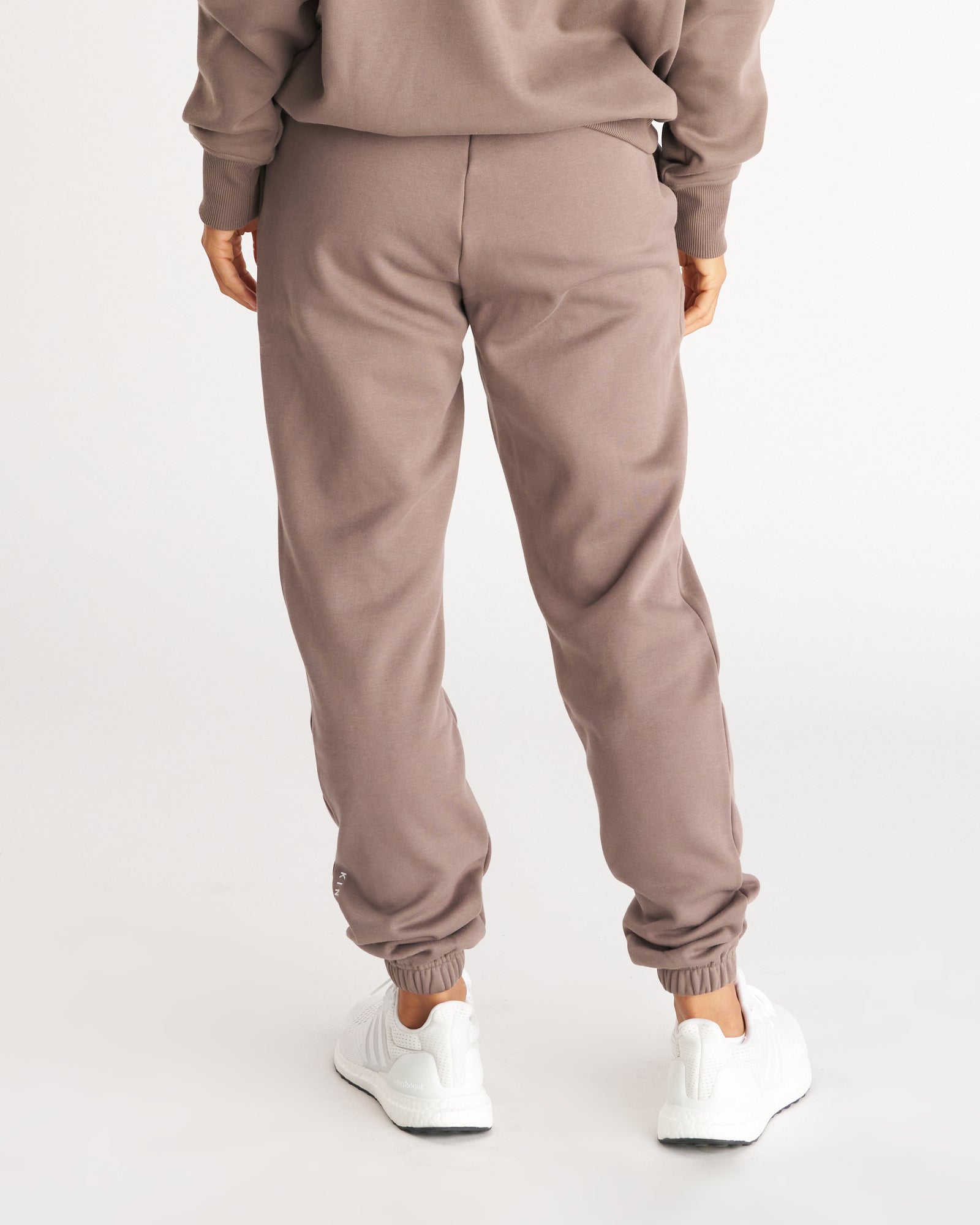 Back view of Deep Taupe Signature Fleece Sweatpants on a model, showing ribbed cuffs and matching hoodie set.