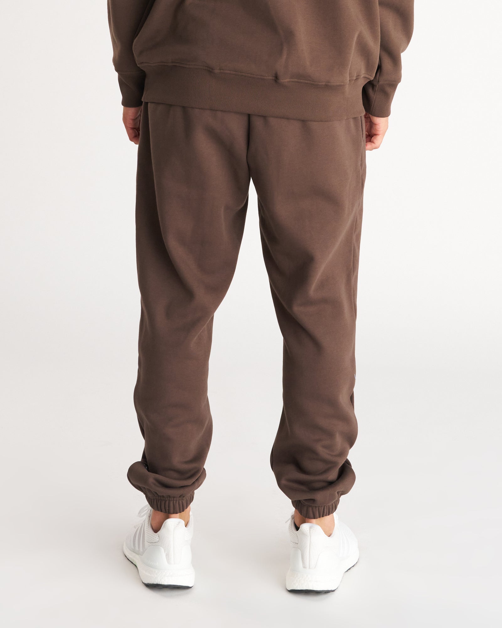 Back view of Signature Fleece Sweatpants in Woodland Brown with ribbed cuffs, paired with white sneakers.