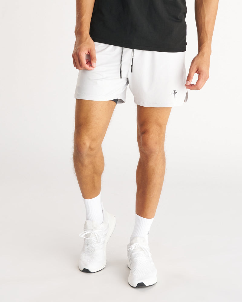 Man wearing white Pro-Tech 2.0 Liner 5" Shorts, front view, paired with black tee and white sneakers.