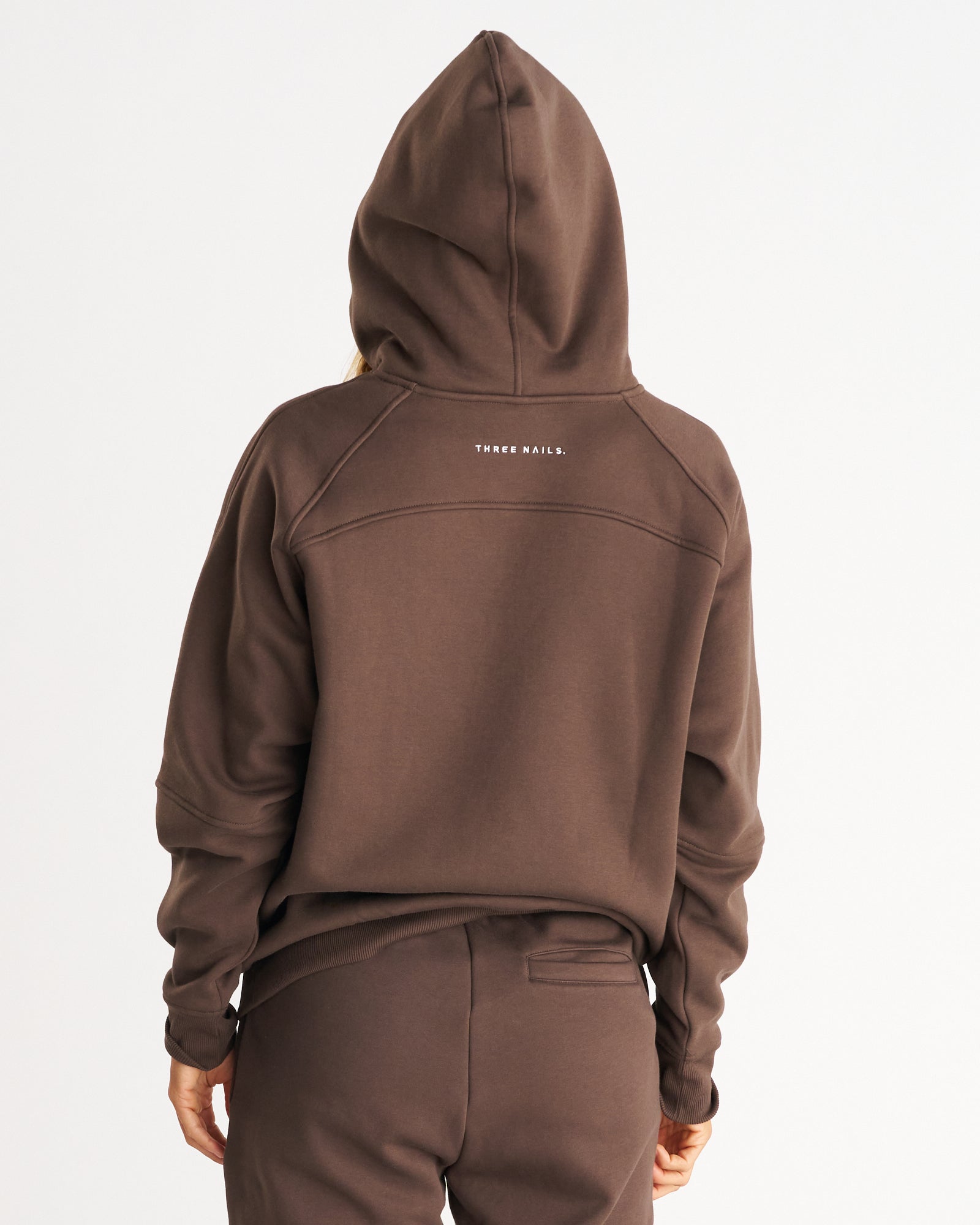 Signature Fleece Hoodie in Woodland Brown, back view on model showing hood up and THREE NAILS. logo text.