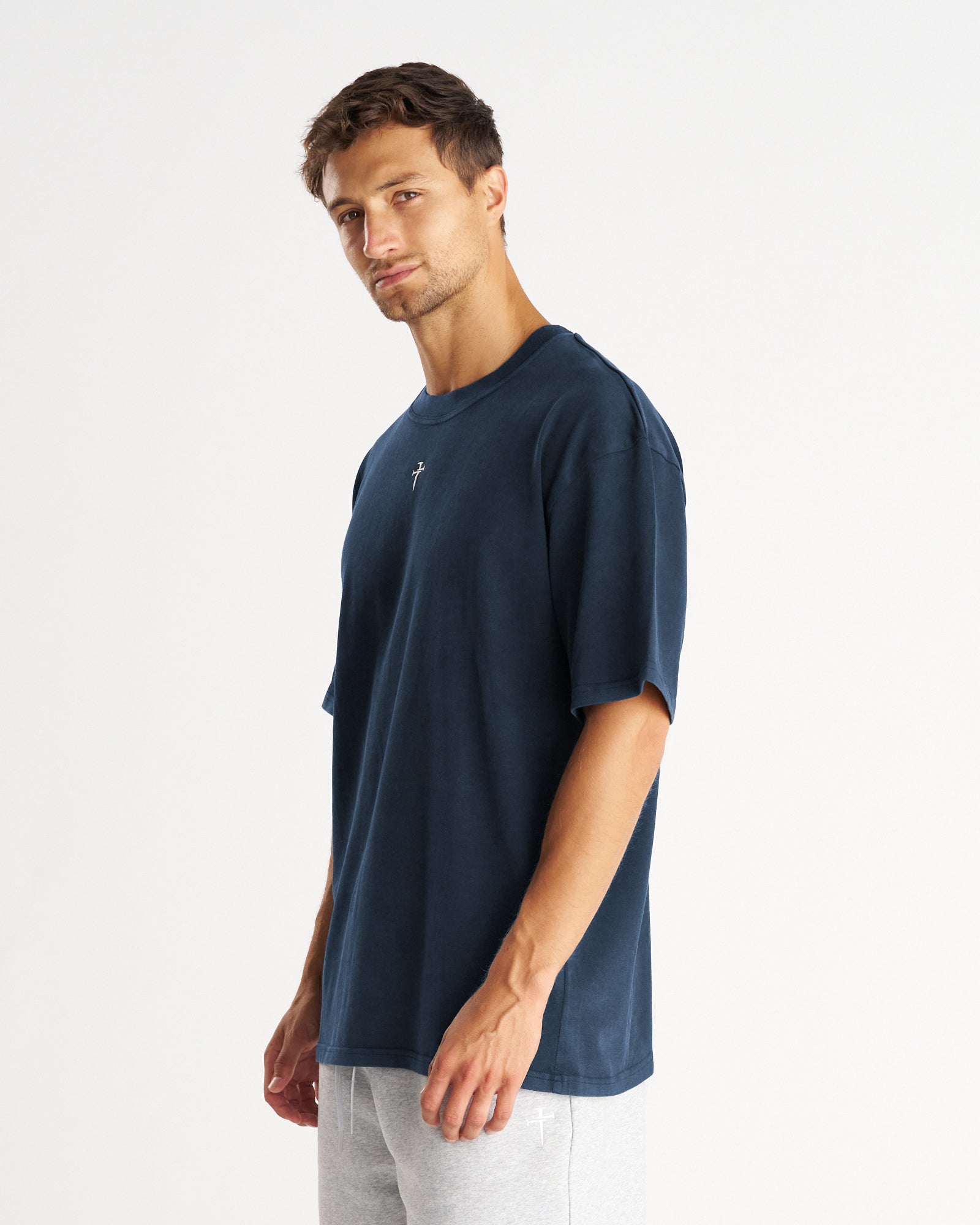 Heavyweight Cotton Oversized Tee FHG in Midnight Navy, male model side angle view, relaxed fit with small cross logo.