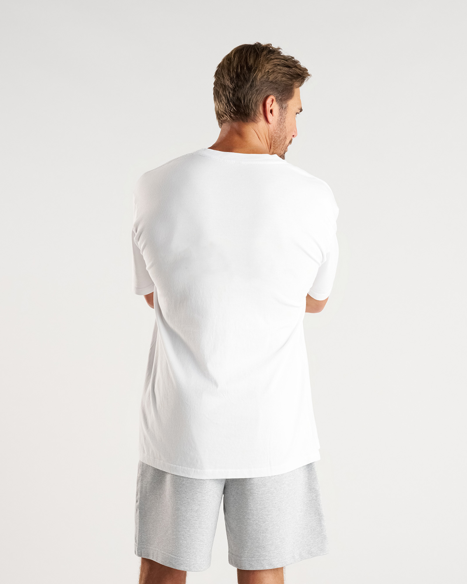 Back view of model wearing the Heavyweight Cotton Oversized Tee in white, paired with grey shorts.
