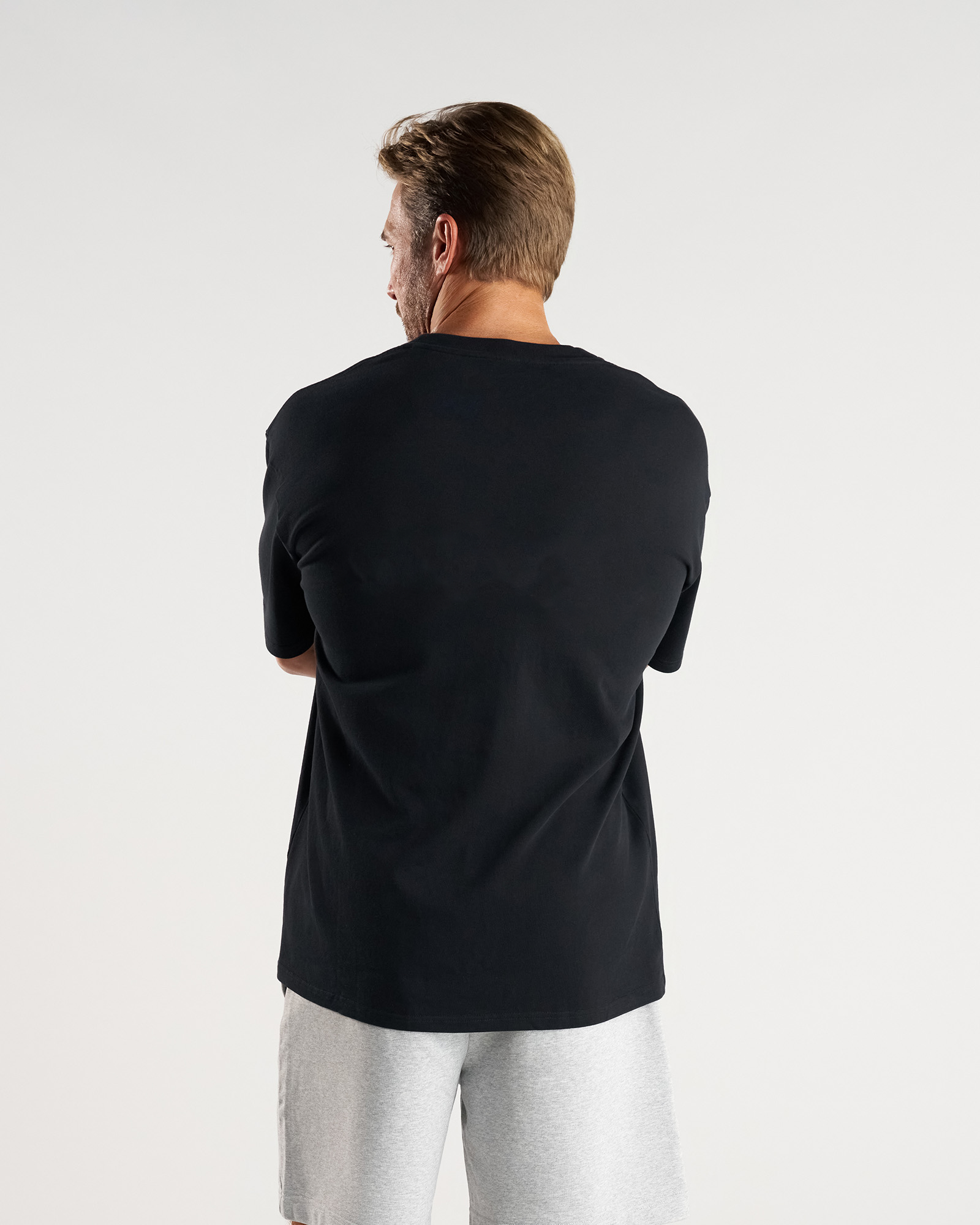 Back view of model wearing the Heavyweight Cotton Oversized Tee in black, paired with grey shorts.