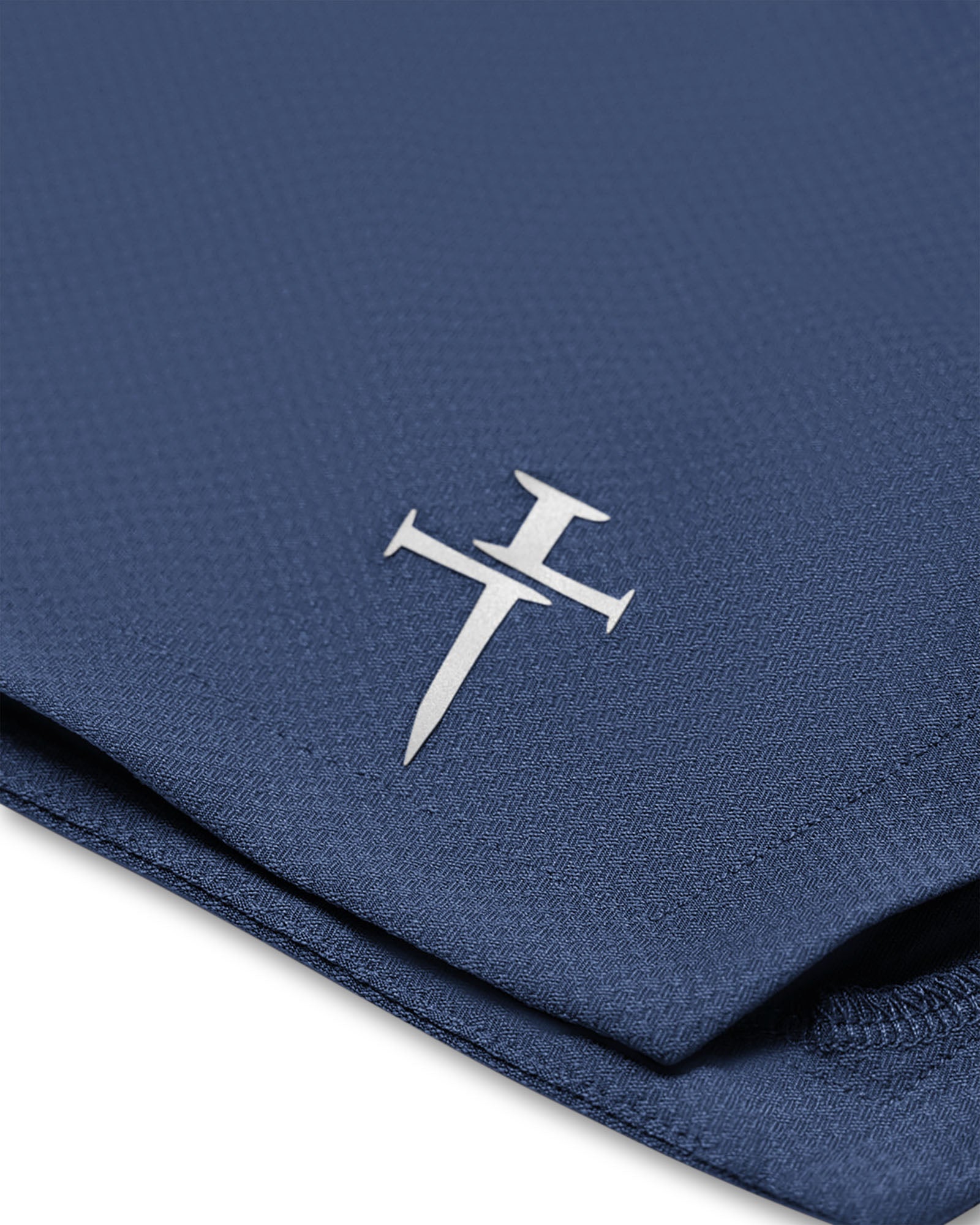 Close-up detail of the Midnight Navy Pro-Tech 2.0 Linerless Short showing the Three Nails logo on folded fabric.