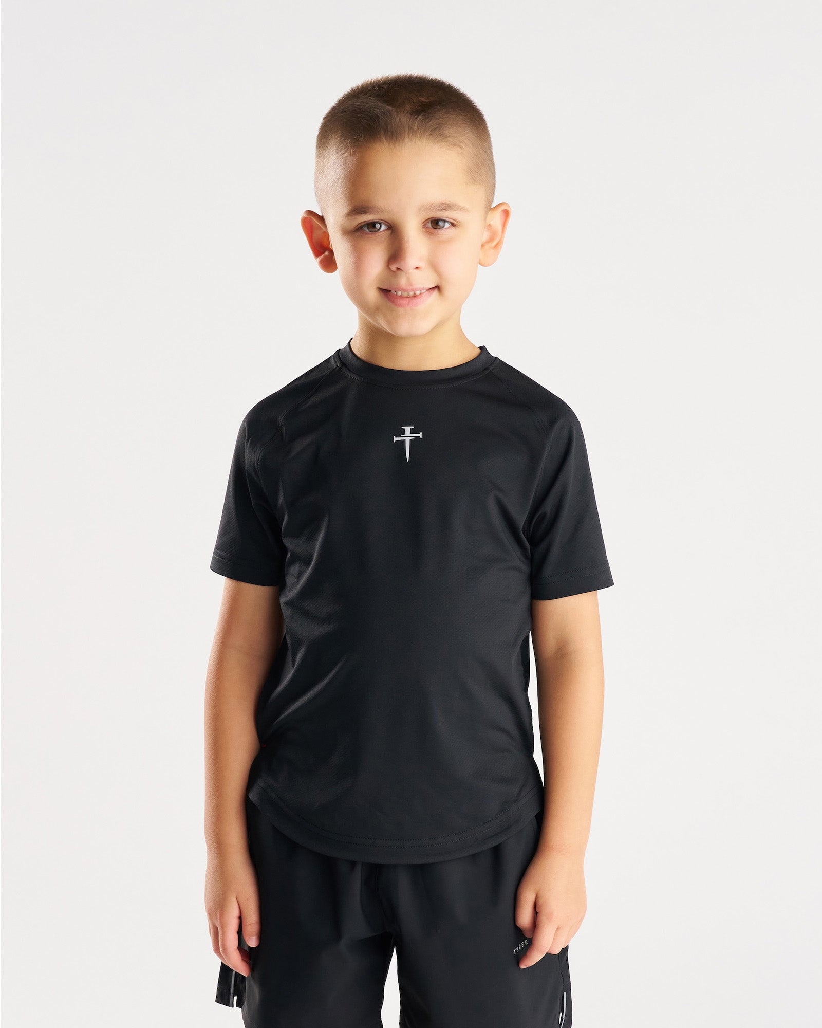 Youth Pro-Tech Tee Cross in black, front view on young boy model with small cross logo at chest.