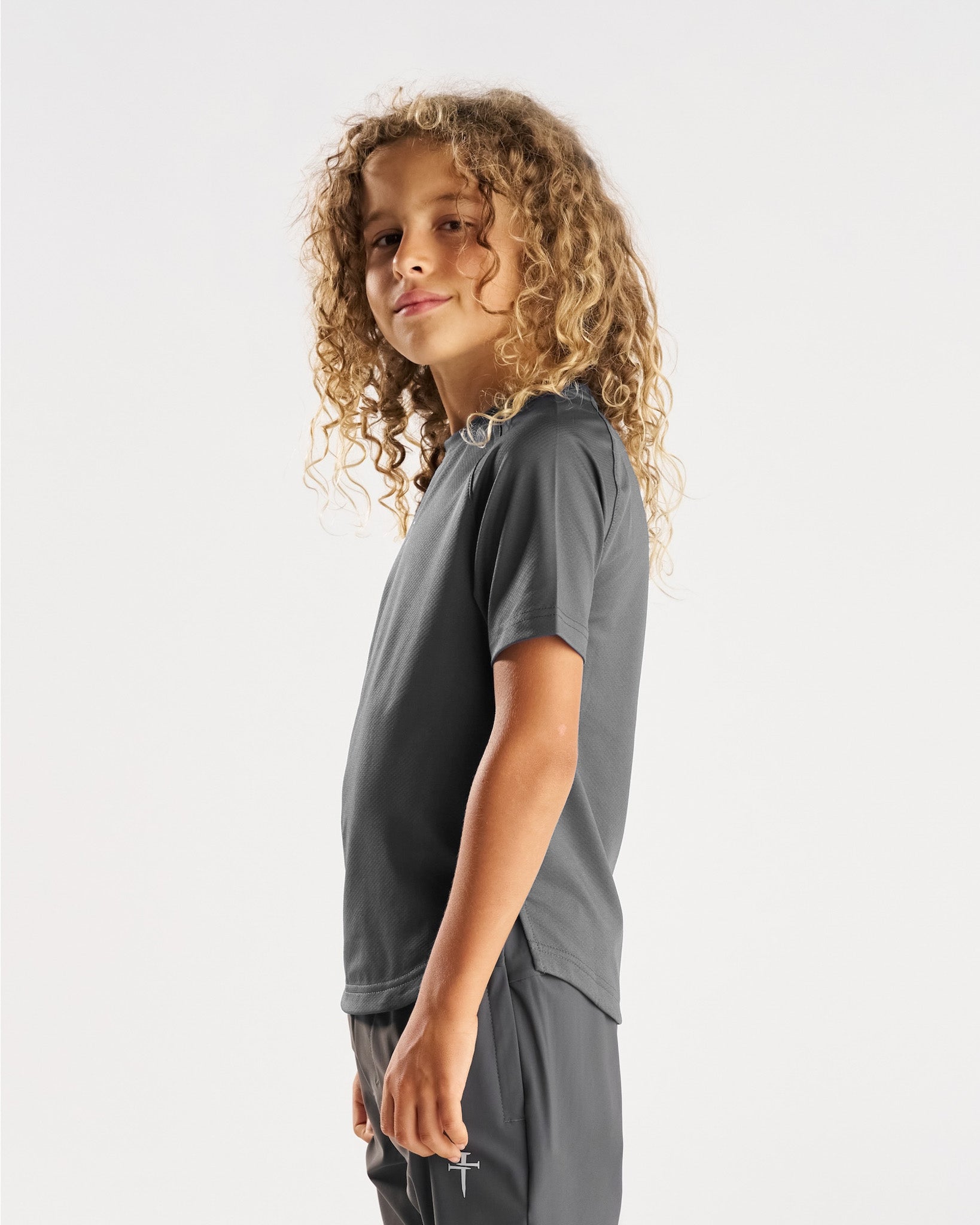 Youth Pro-Tech Tee Cross in Space Grey on a child model shown from a side angle against a white background.