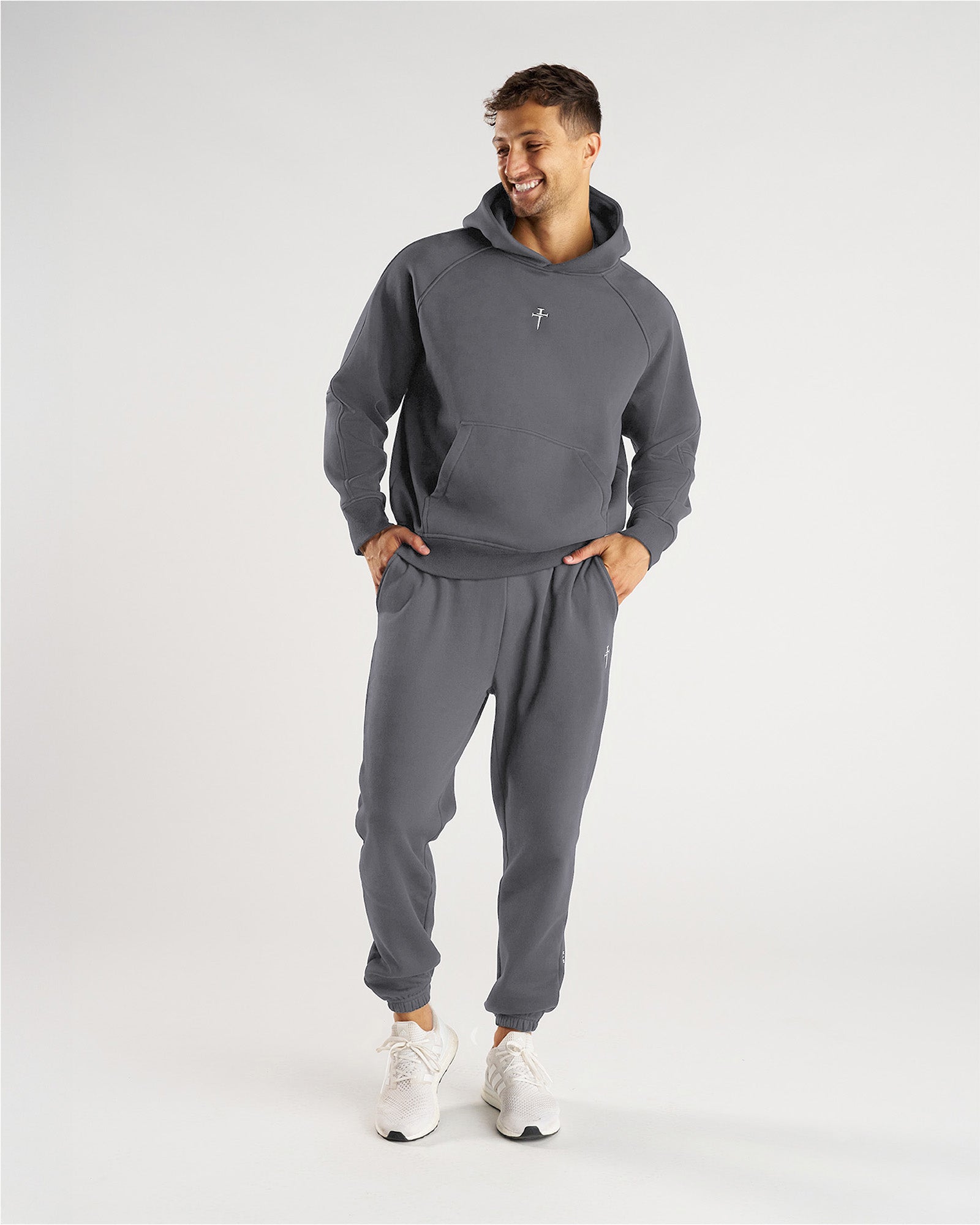 Man wearing Signature Fleece Sweatpants in Space Grey, front view, paired with matching hoodie and white sneakers.