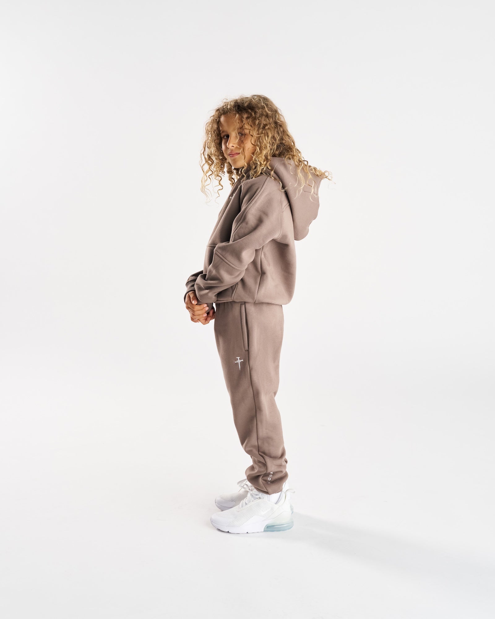 Youth Signature Fleece Hoodie in Deep Taupe on a child model shown from a side angle, paired with matching joggers.