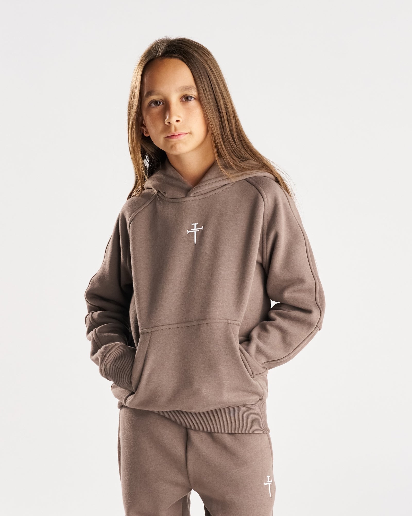 Youth Signature Fleece Hoodie in Deep Taupe on a young model, front three-quarter view, paired with matching sweatpants.