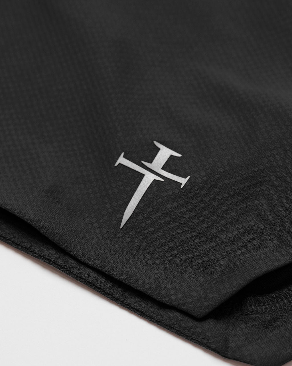 Close-up of the Black Pro-Tech 2.0 Liner Short showing the silver Three Nails logo on folded fabric.
