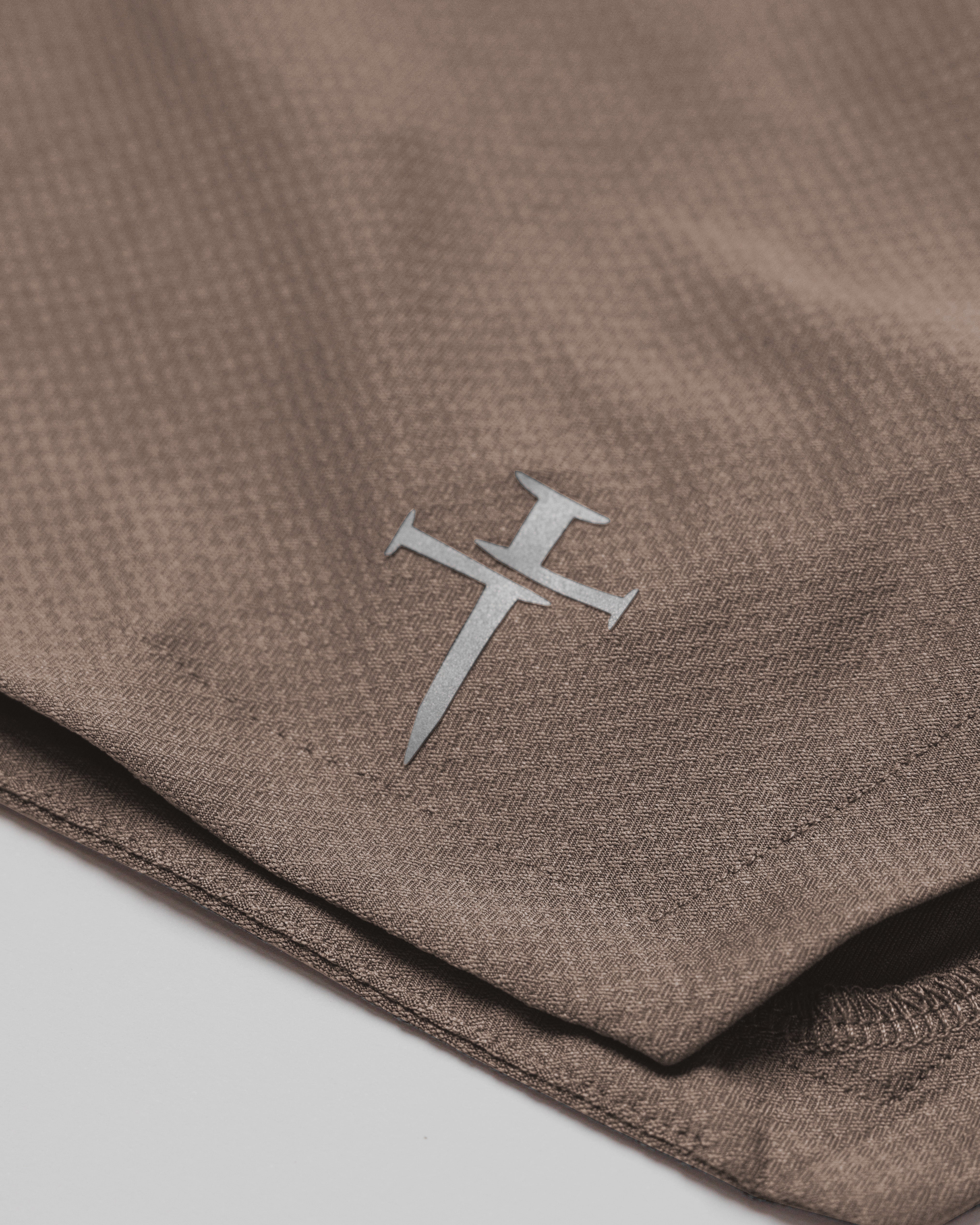 Close-up of the Three Nails logo on the Pro-Tech 2.0 Liner Short in Deep Taupe.