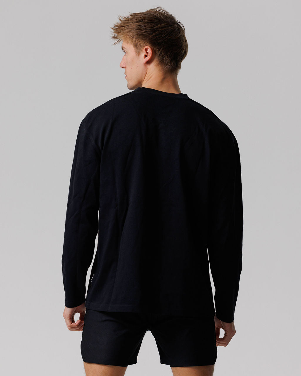 Back view of model wearing the Heavyweight Cotton Oversized Long Sleeve in black with matching black shorts.