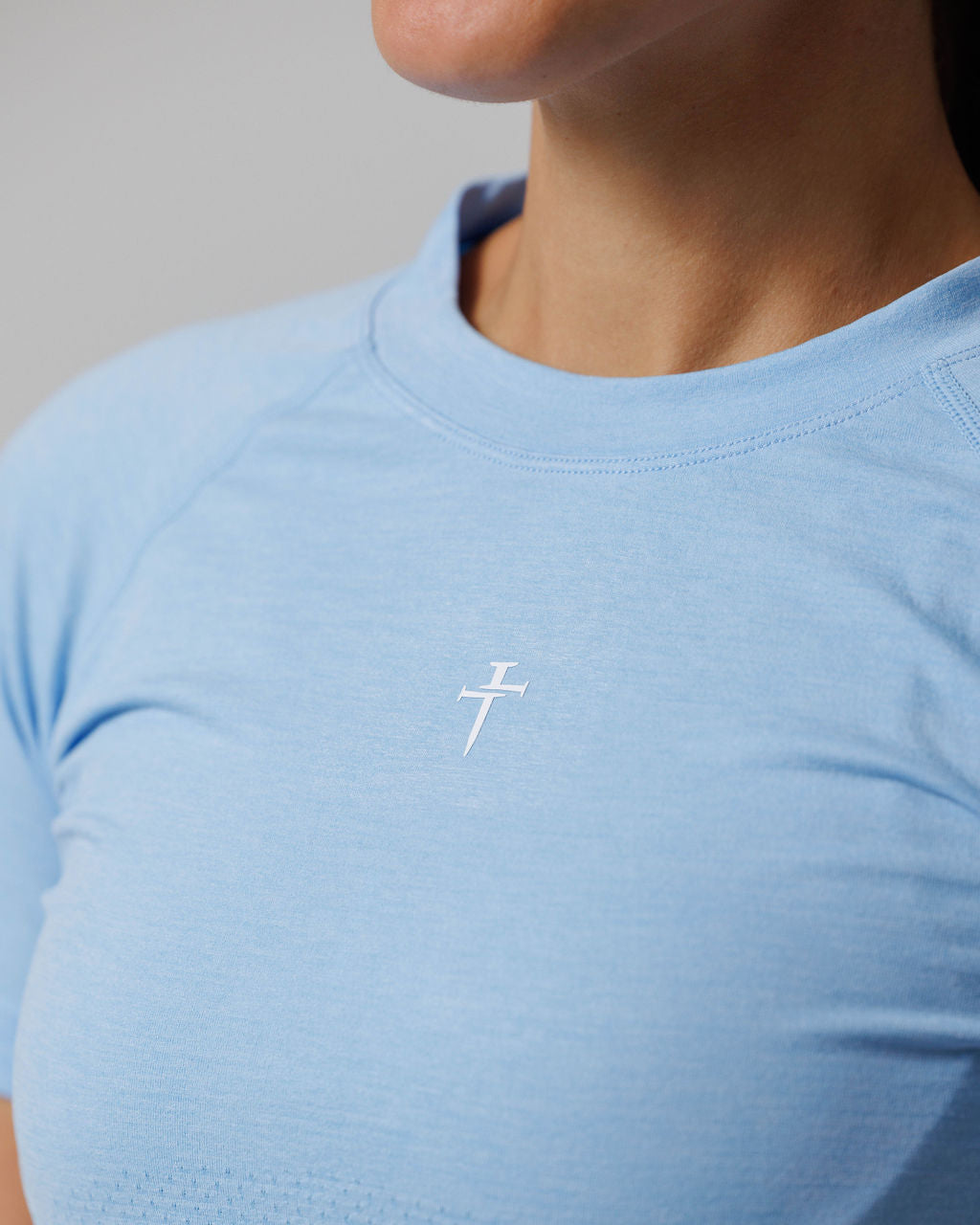 Close-up of Women's Seamless Tee Cross in Sky Blue showing the white cross logo detail on the chest.