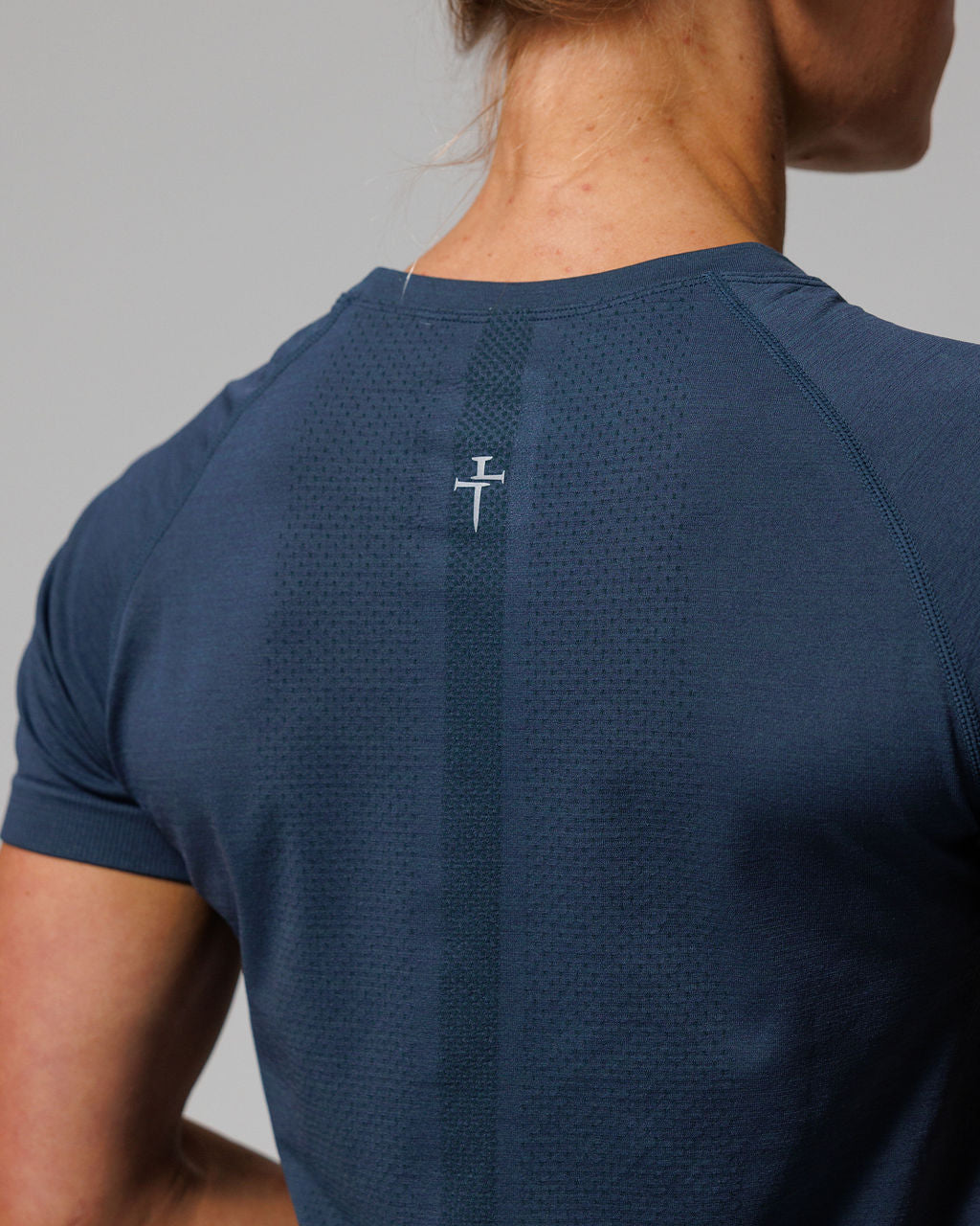Close-up back view of Womens Seamless Tee Minimal in Midnight Navy showing logo detail and textured knit pattern.