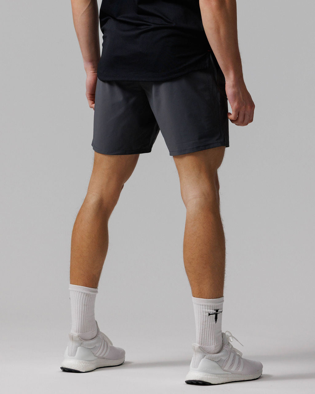 Back view of model wearing Vapor-Lite Hybrid Short in Space Grey with white sneakers and socks.