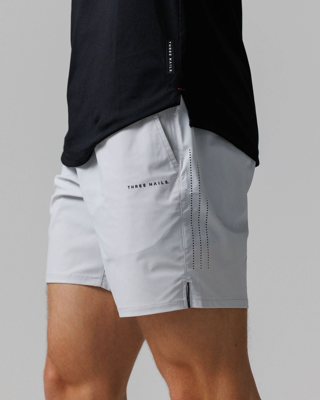 Side angle close-up of Vapor-Lite Hybrid Short in Stone, showing perforated panel detail and brand logo.