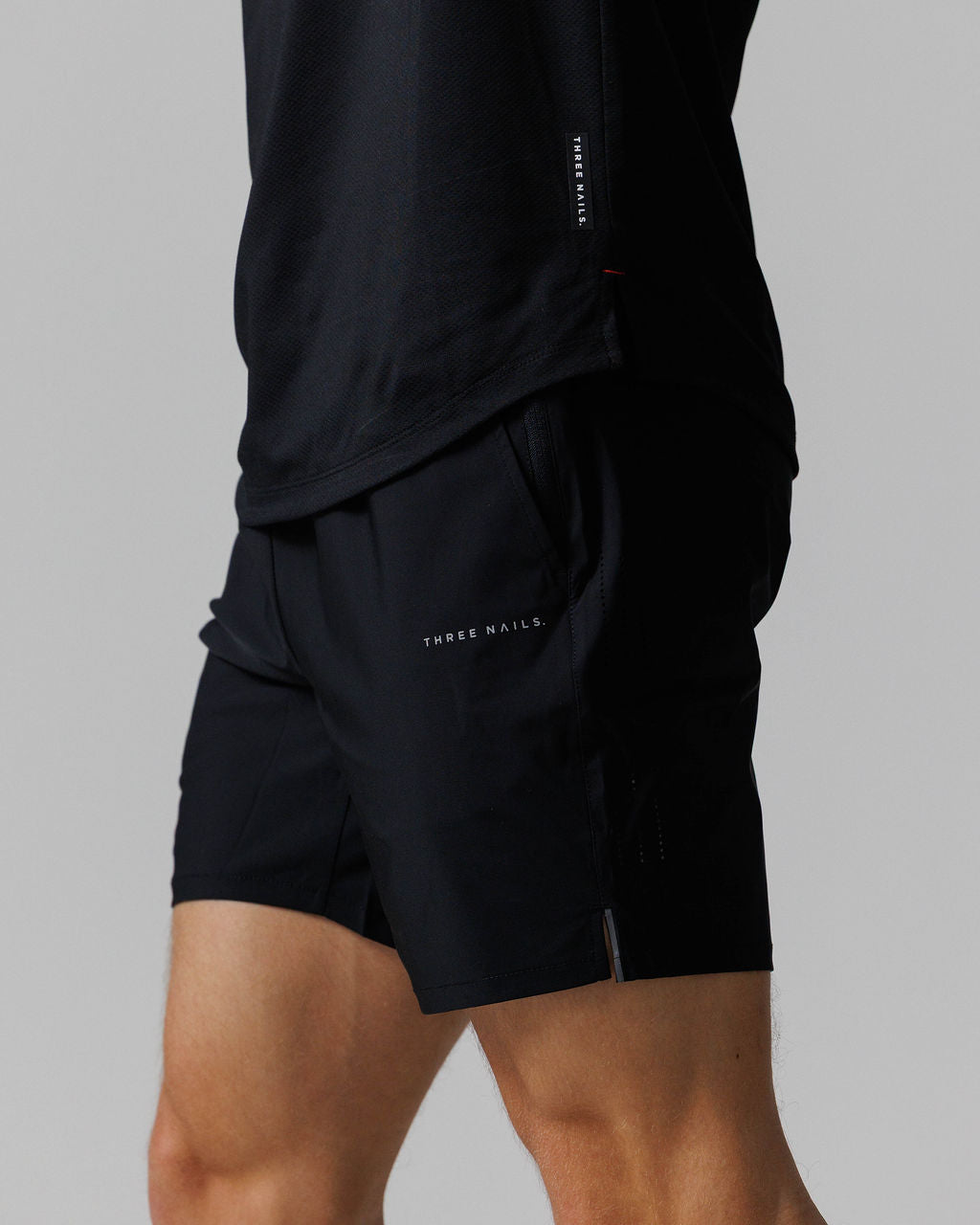 Close-up side angle of the Vapor-Lite Hybrid Short in black, showing pocket detail and hem vent.