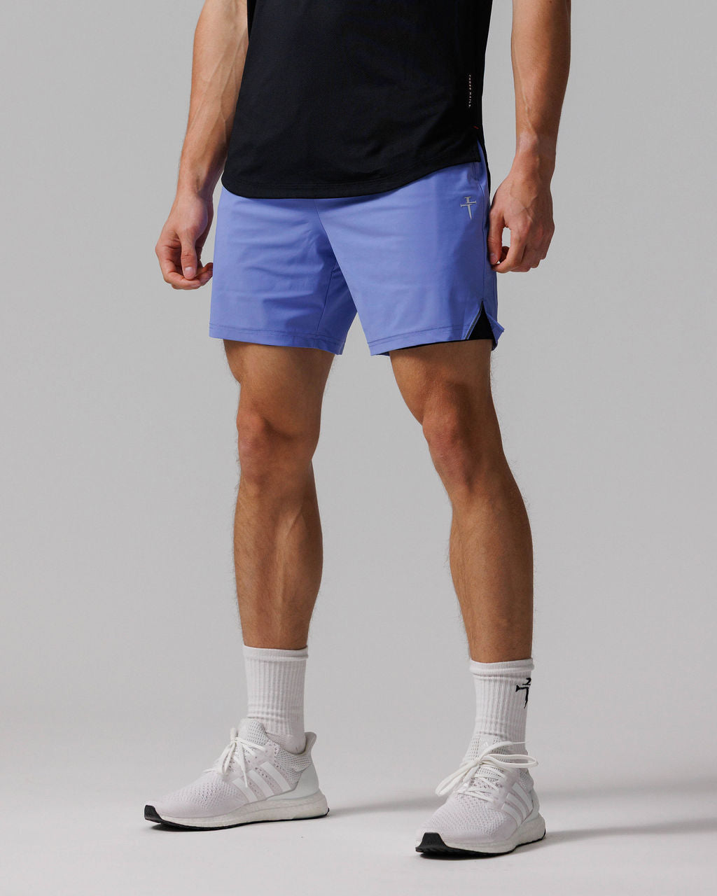 Man wearing Vapor-Lite Liner Short Cross in Serene Blue, side-angle view, paired with black tee and white sneakers.