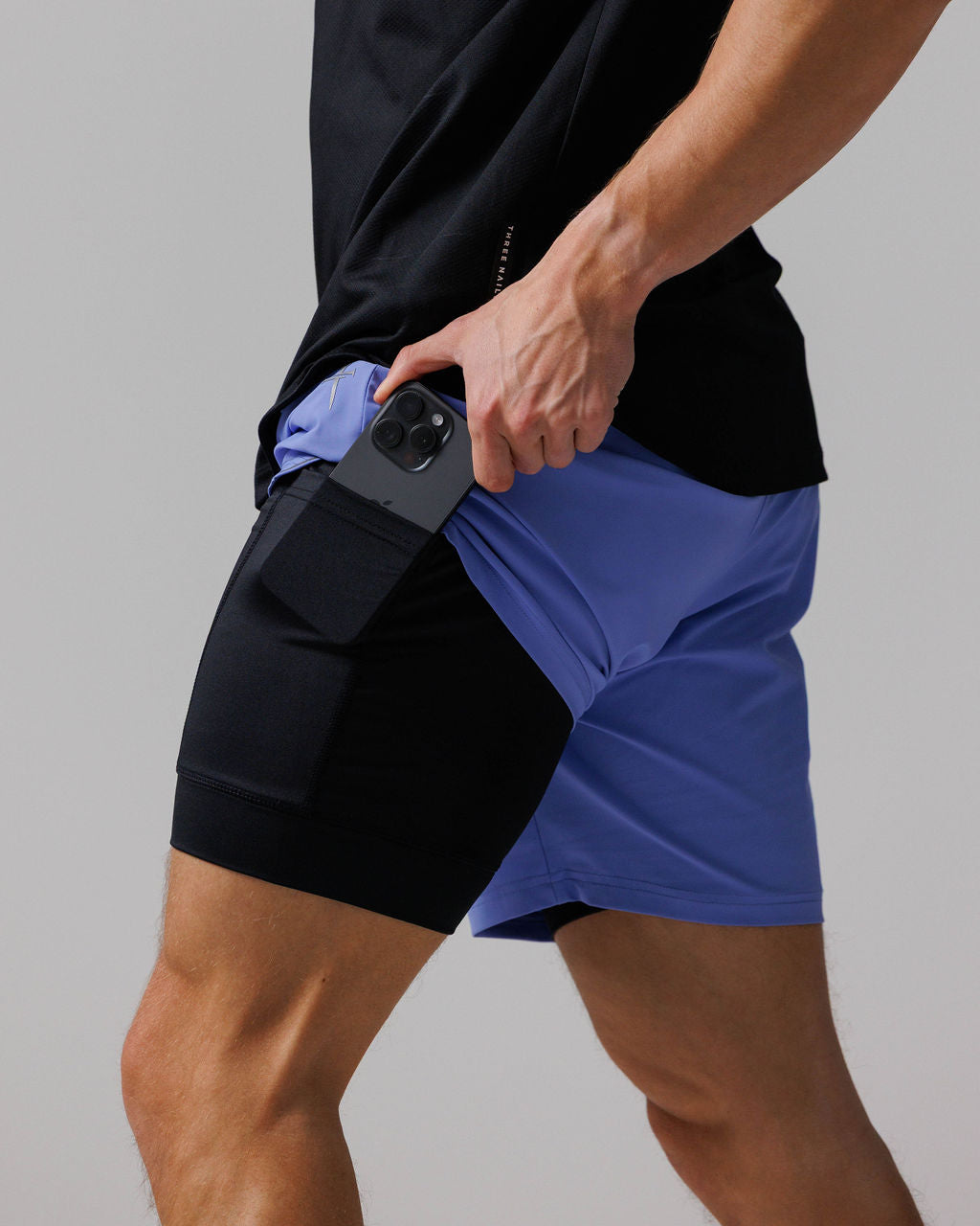 Side angle close-up of Vapor-Lite Liner Short Cross in Serene Blue showing phone being inserted into inner liner pocket.