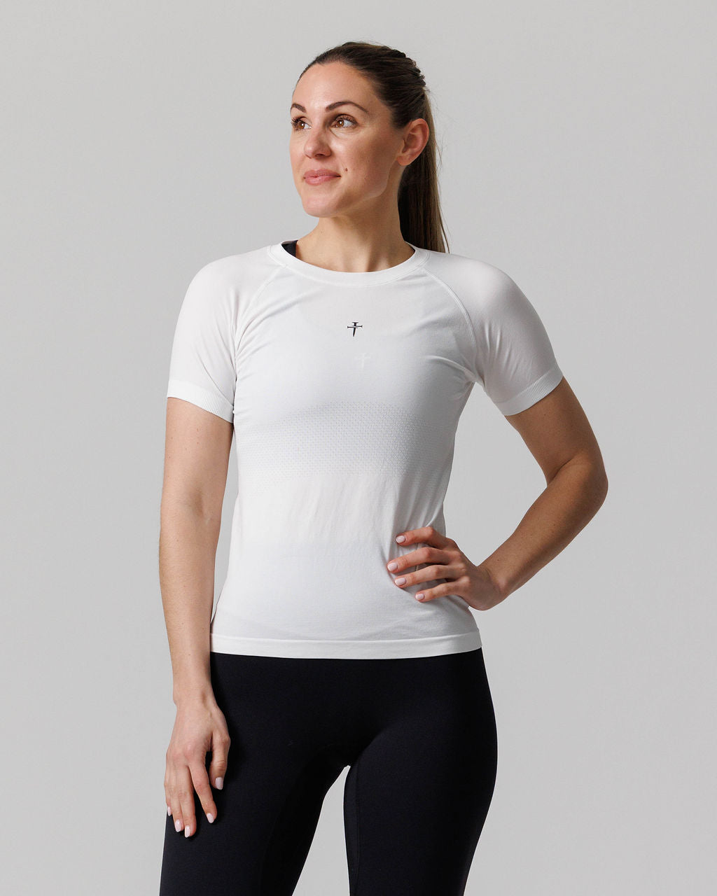 Women's Seamless Tee Cross in white, front view on model with one hand on hip.
