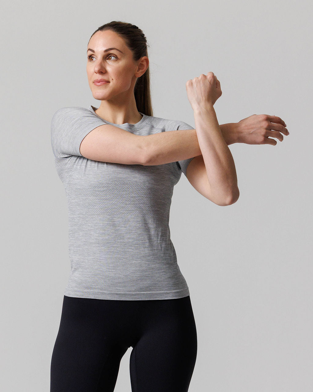Woman wearing the Womens Seamless Tee Cross in Grey Marl, front view, arms crossed in a stretch pose.