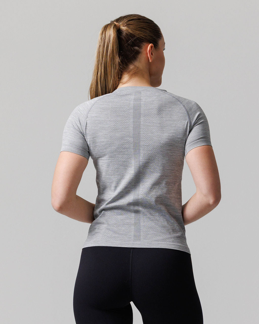Women's Seamless Tee Cross in Grey Marl, back view on model wearing black leggings with hair in ponytail.