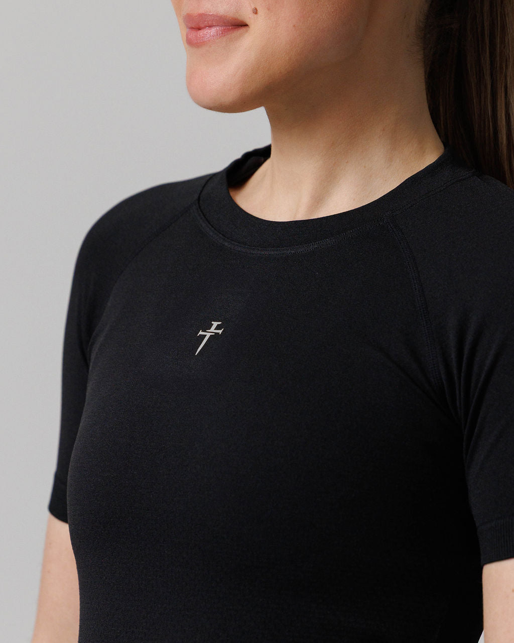Close-up of Women's Seamless Tee Cross in black showing the silver cross logo on the chest.