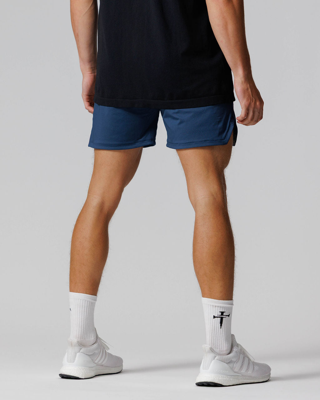 Back view of model wearing Pro-Tech 2.0 Linerless Short in Midnight Navy with white Adidas sneakers.