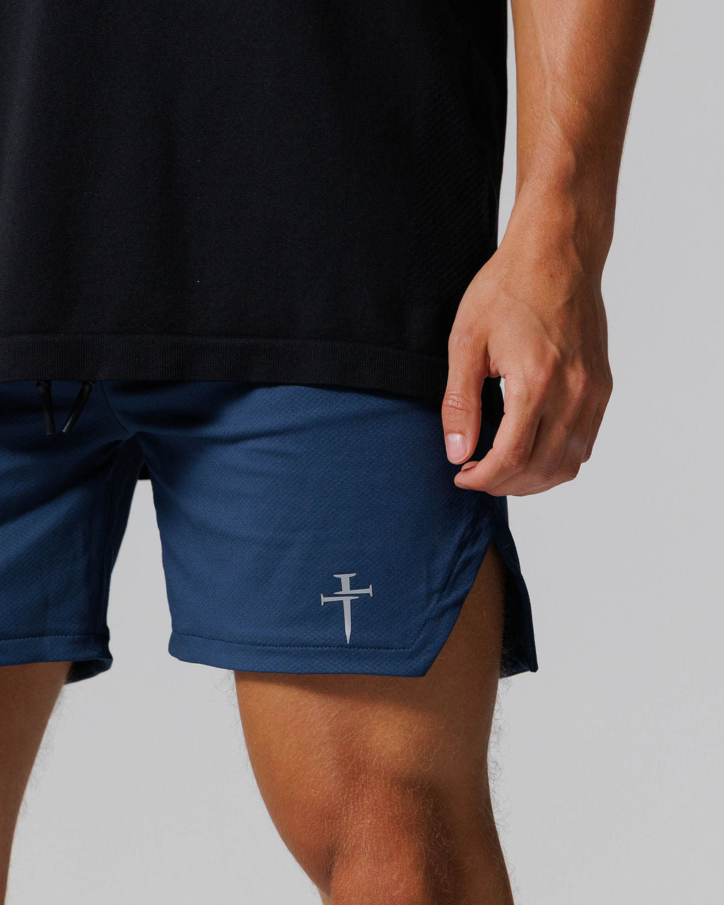 Close-up detail of Pro-Tech 2.0 Linerless Short in Midnight Navy showing the Three Nails logo and side hem.