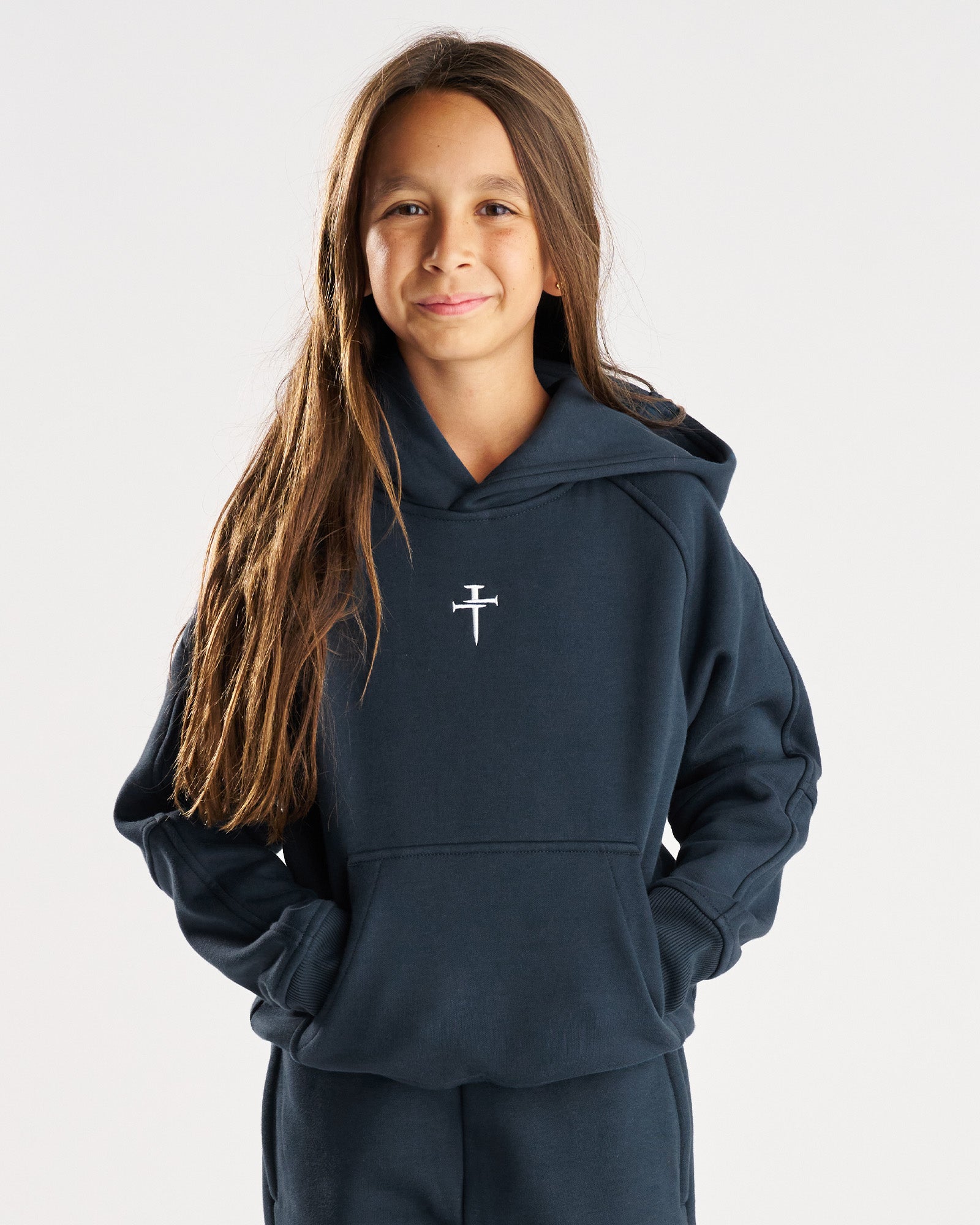 Youth Signature Fleece Hoodie in Midnight Navy, front view on a young model with a small nail cross logo at center chest.