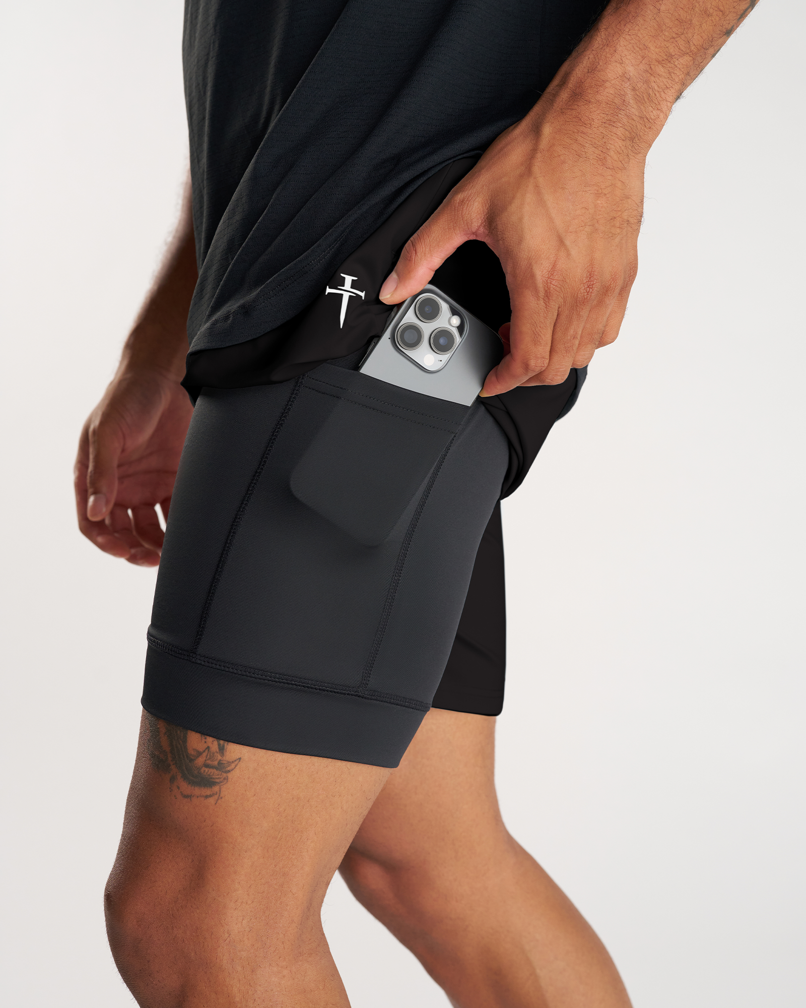 Side angle close-up of Vapor-Lite Liner Short Cross in black showing a phone being placed into the side pocket.
