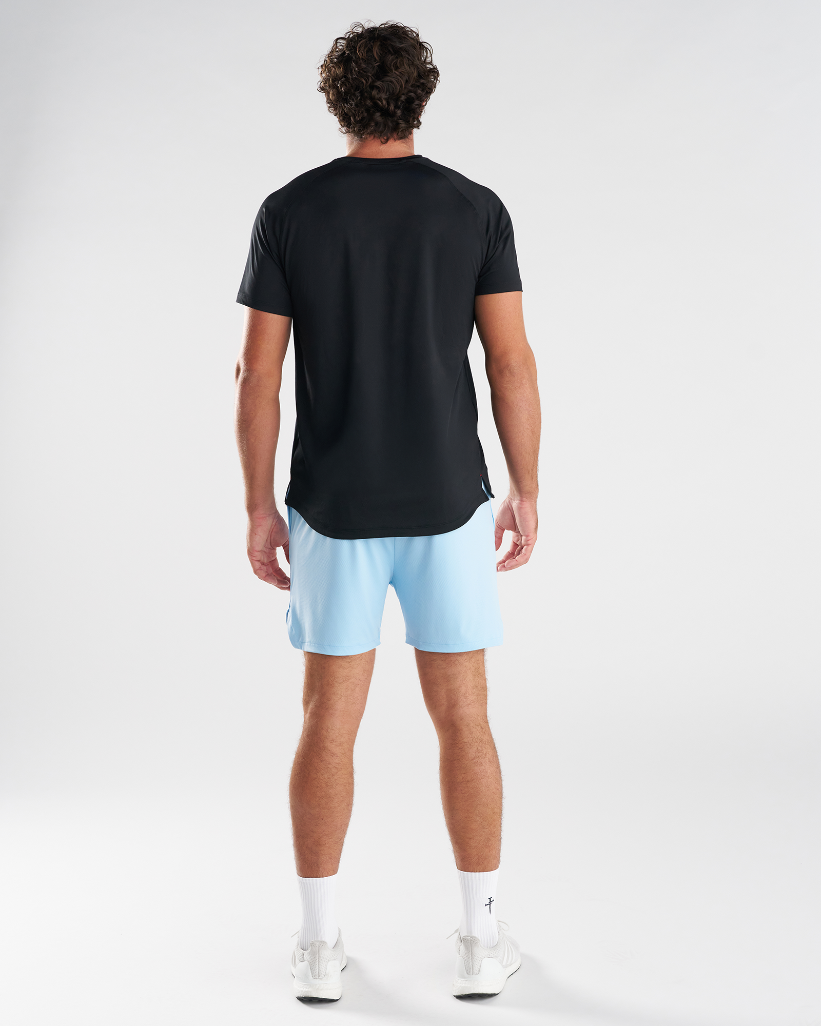 Back view of model wearing Pro-Tech 2.0 Liner Short in Sky Blue paired with a black tee and white sneakers.