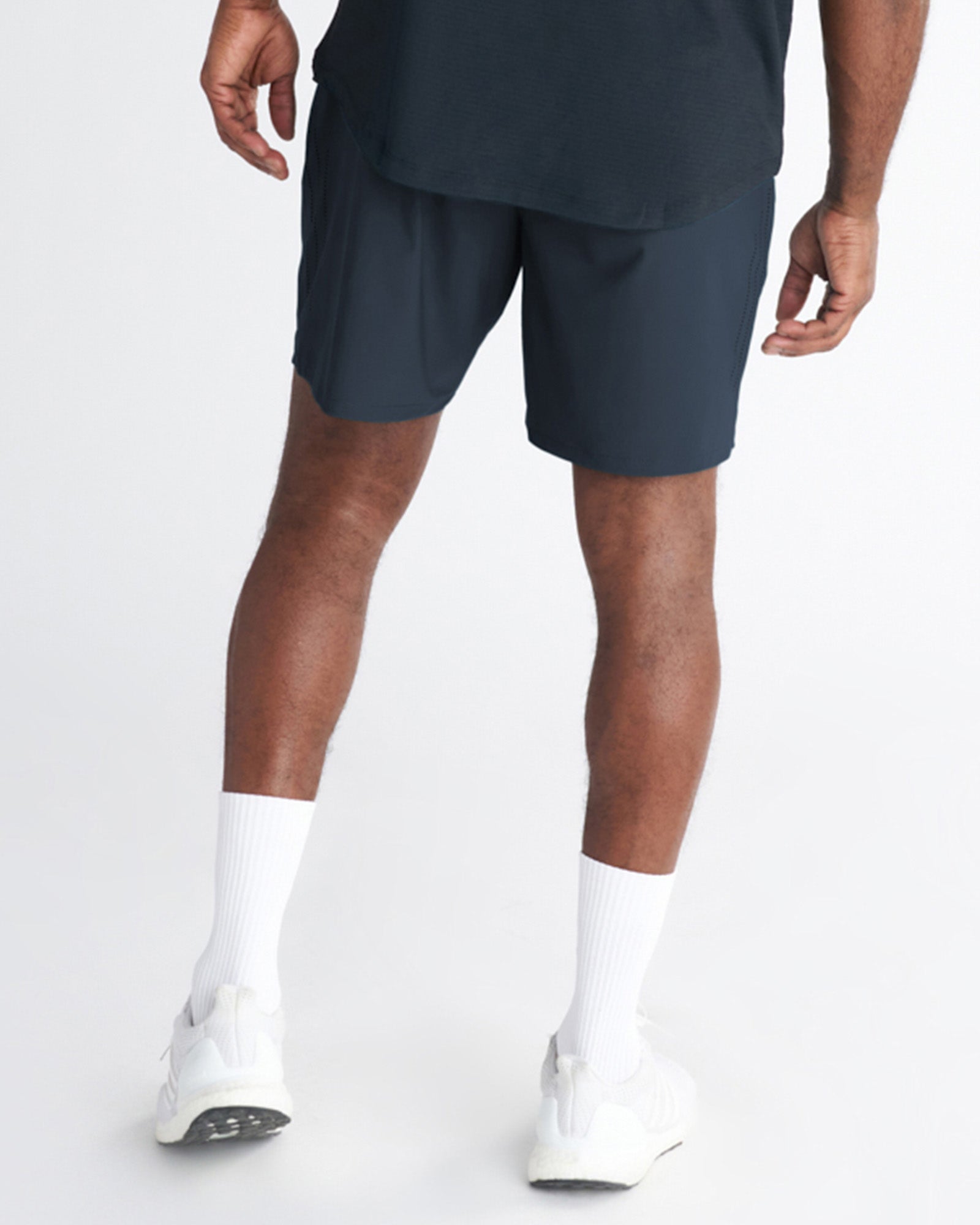 Back view of model wearing Vapor-Lite Hybrid Short in Midnight Navy with white sneakers and socks.