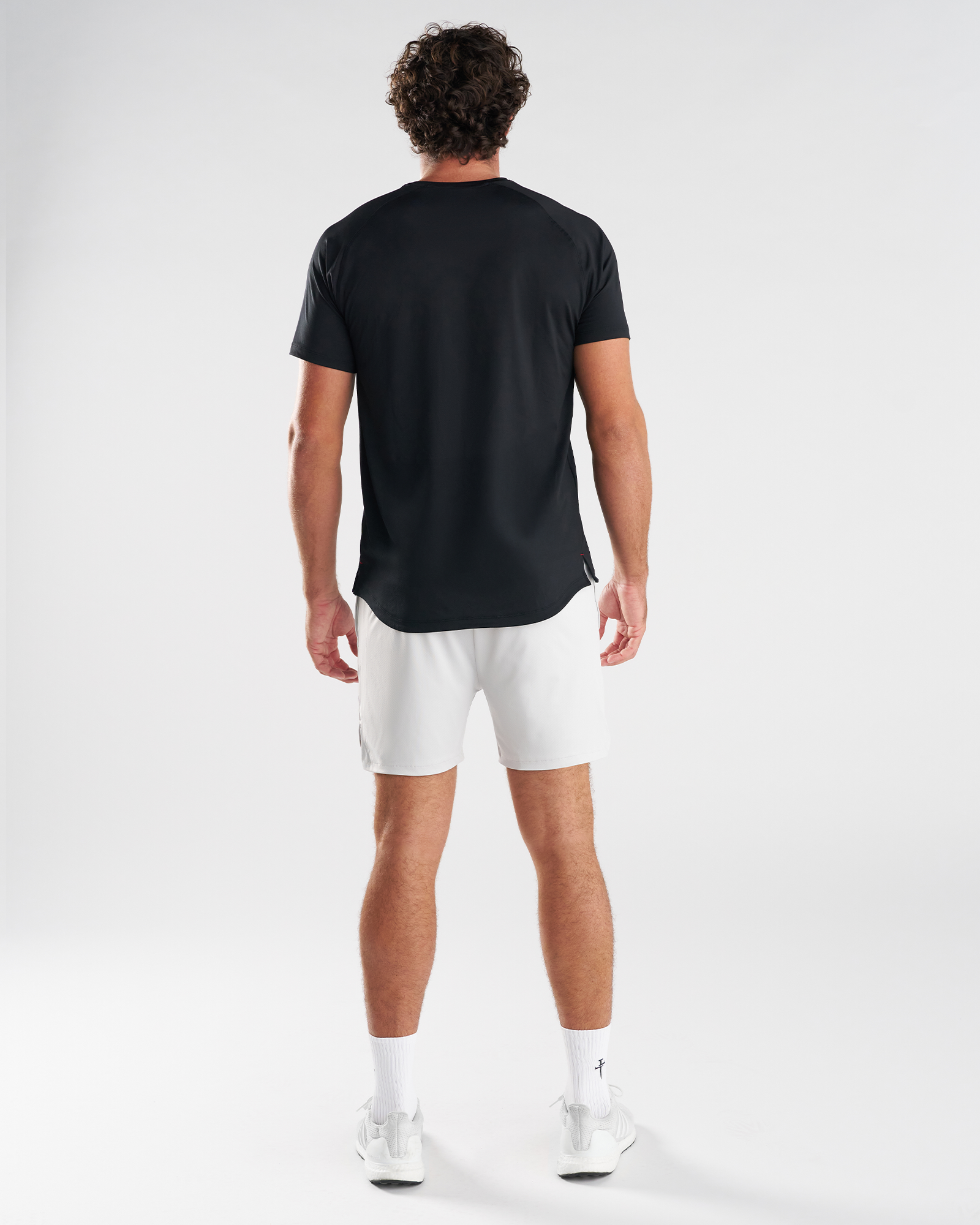 Back view of model wearing the Pro-Tech 2.0 Liner Short in Stone with a black tee and white sneakers.
